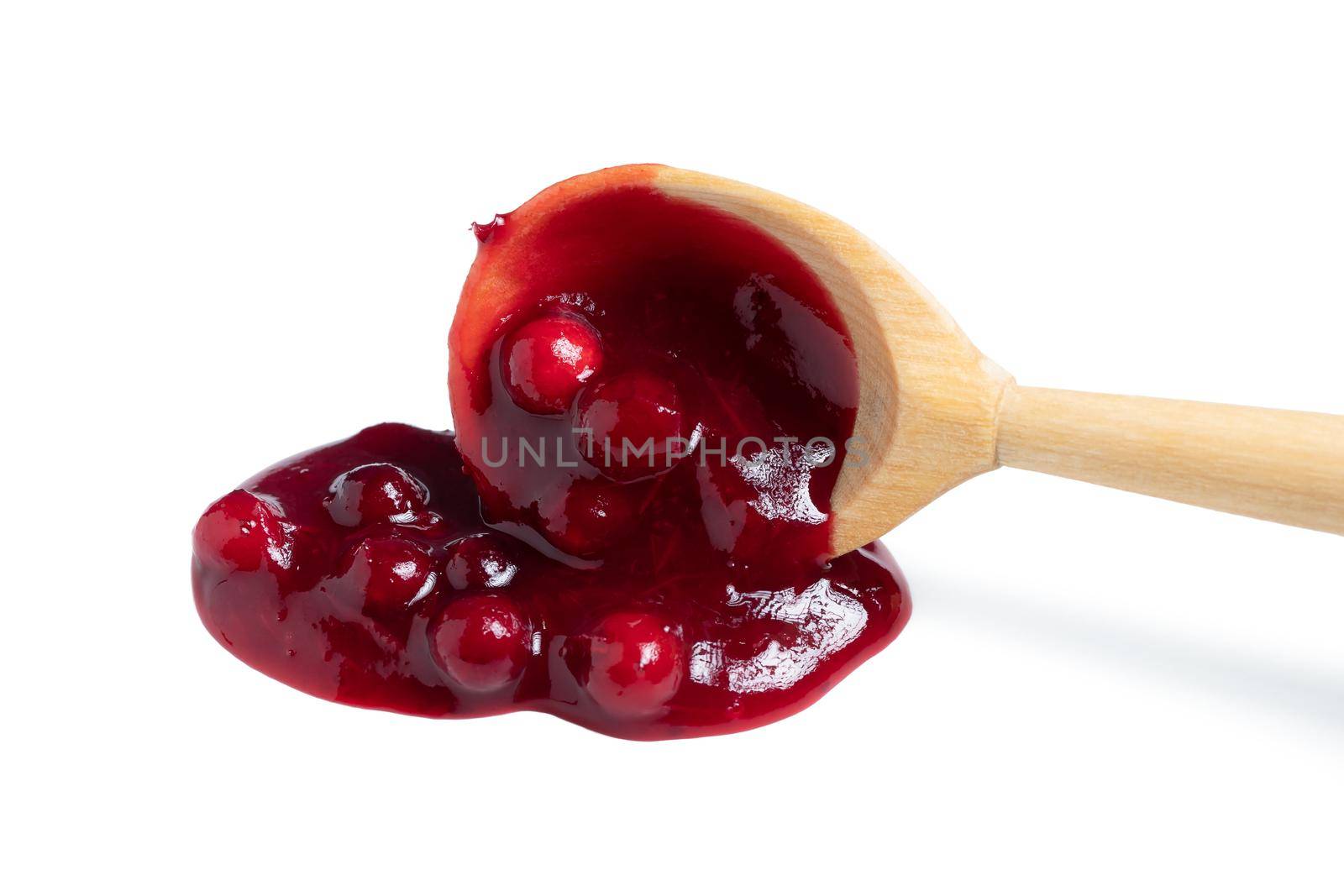 Homemade sauce made from fresh wild lingonberry drips from a spoon. Isolated on white background by galsand