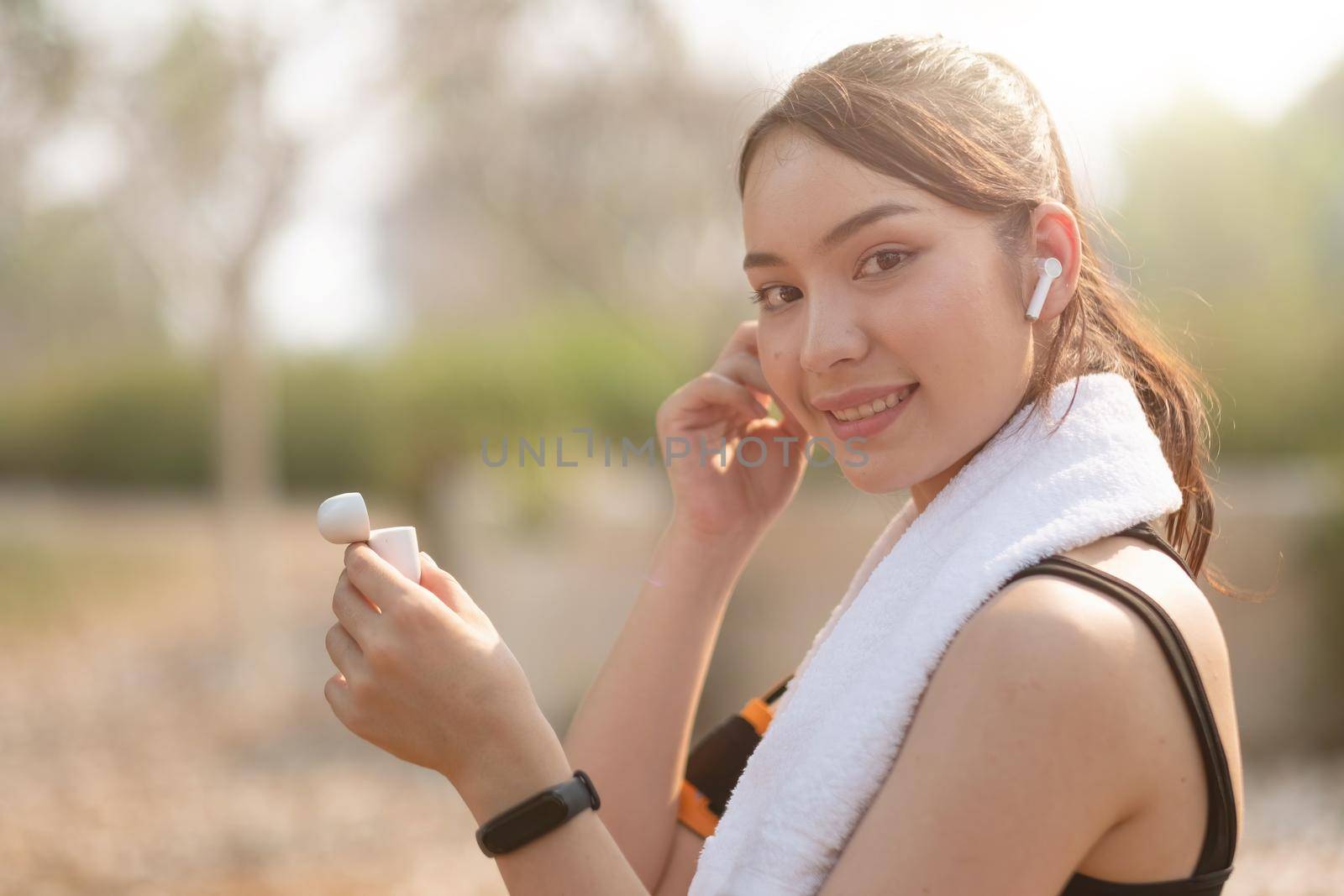 Photo of a beautiful asian young fitness woman running outdoors listening music with earphones by nateemee