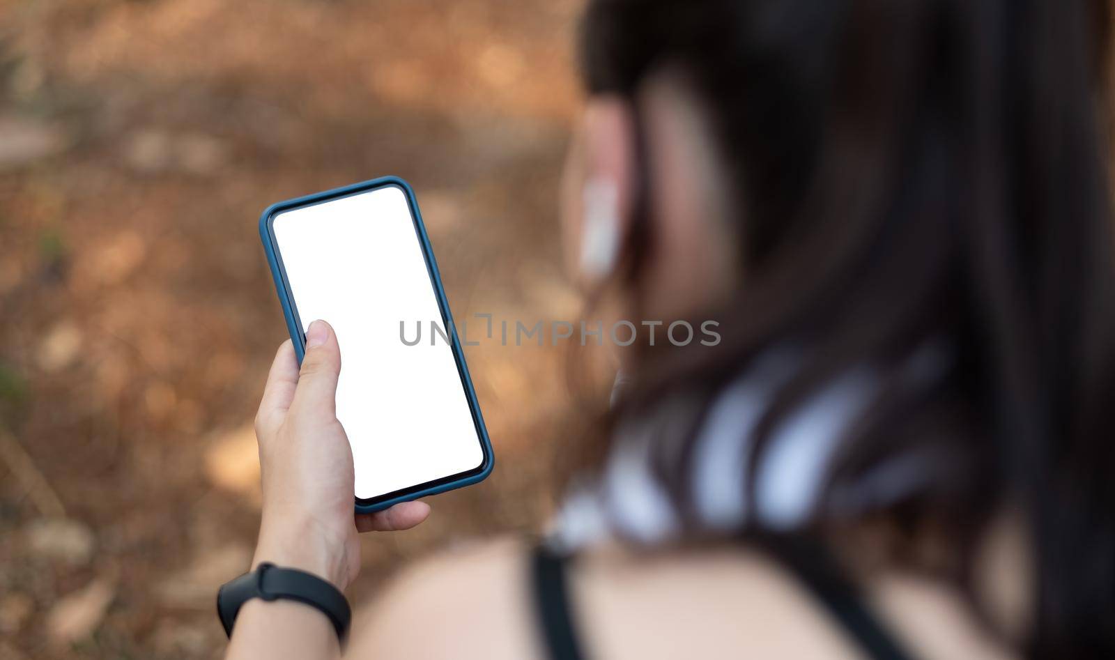 Young sporty woman holding mobile phone with blank screen indoors, closeup view. Mockup for design. by nateemee