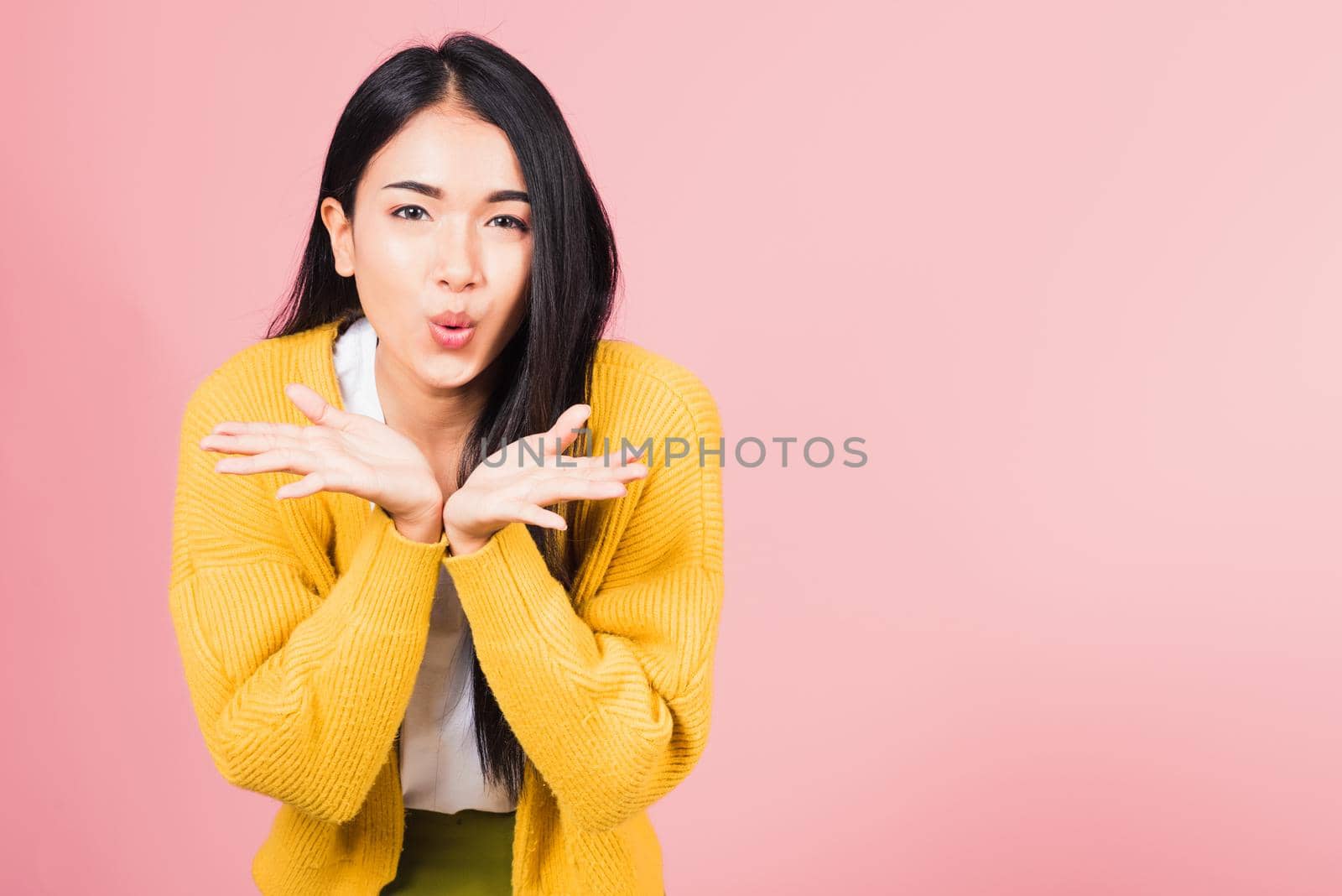 Asian happy portrait beautiful cute young woman teen standing blowing kiss air something on palm hands expresses her love looking to camera studio shot isolated on pink background with copy space