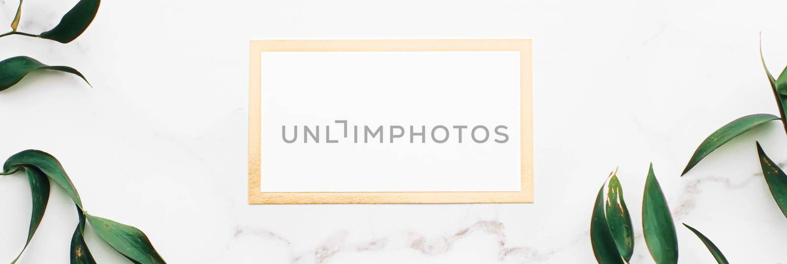 Blank white and gold card, green leaves on white background as botanical frame flatlay, wedding invitation and branding, flat lay design concept