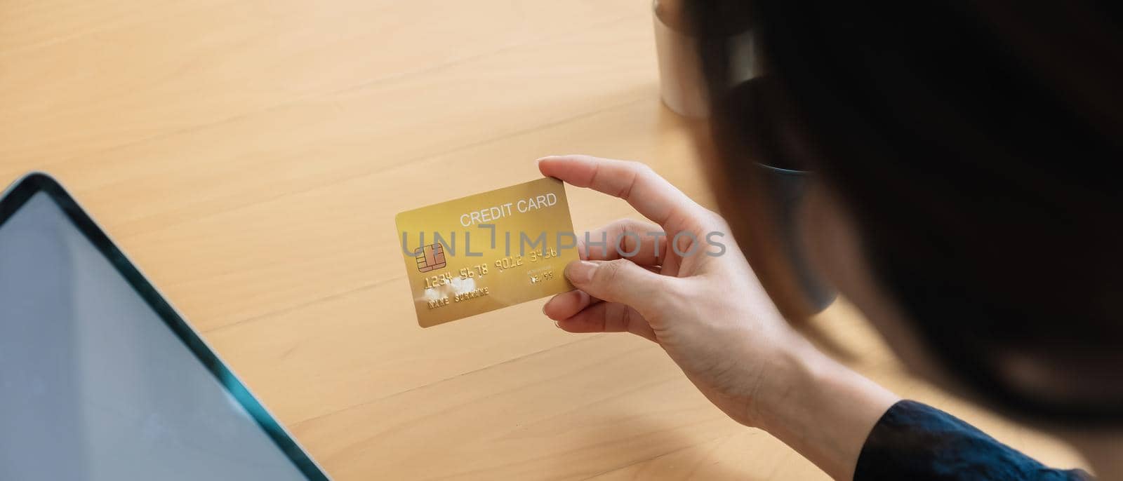 Close up of woman holding credit card and using digital tablet. Businesswoman working at home. Online shopping, e-commerce, internet banking, spending money, working from home concept