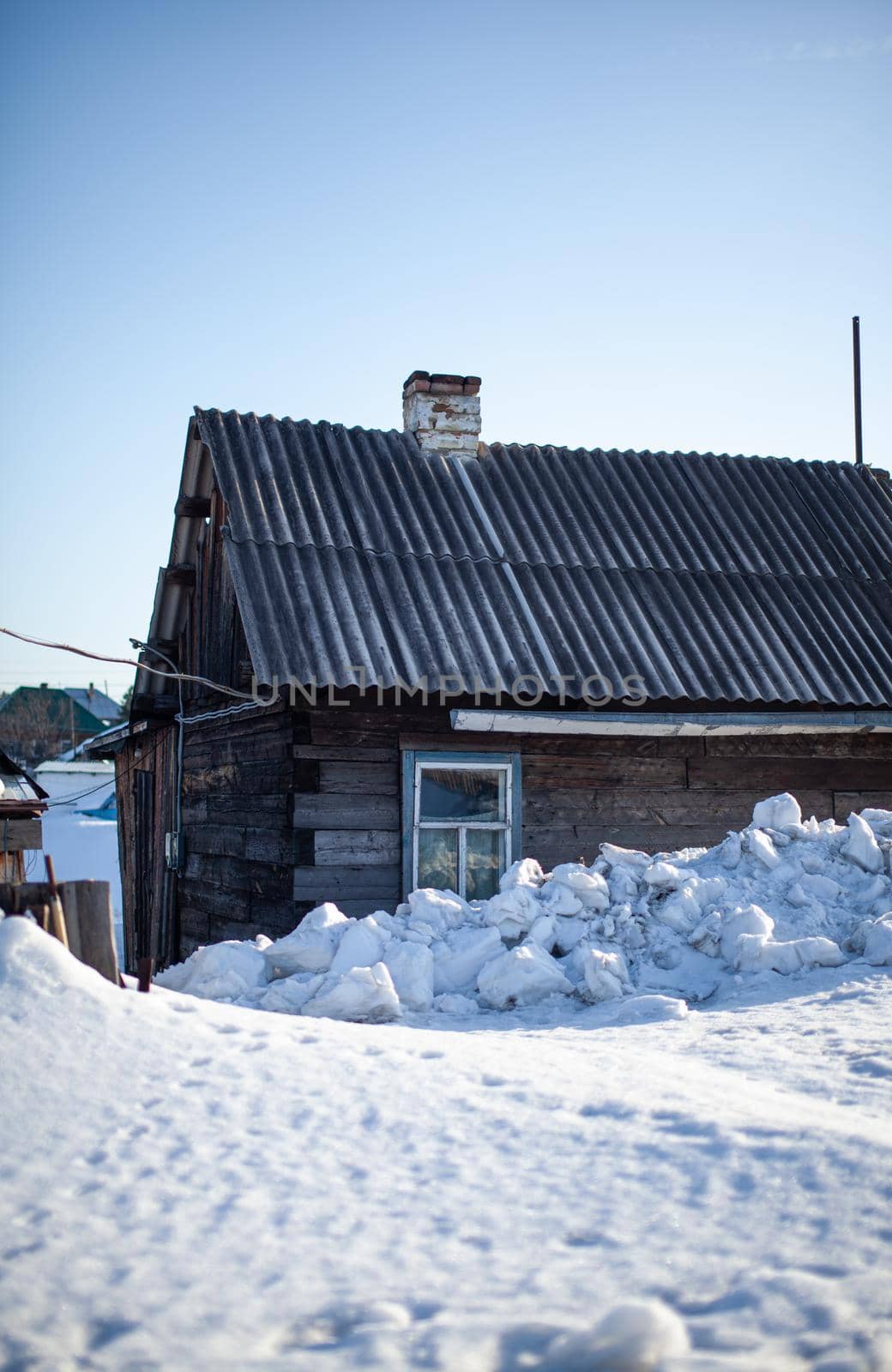 Lots of snow after a snow storm in winter. Houses in the snow captivity. The wooden fence near the houses is covered with snow.