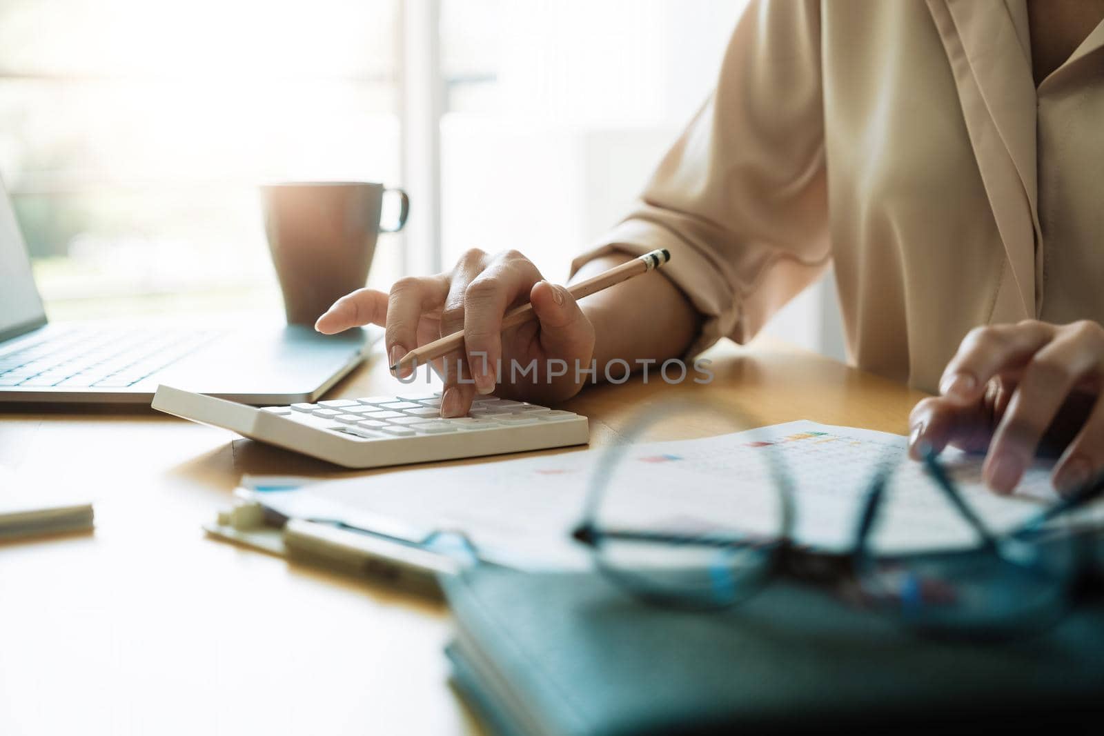 Close up female accountant analyzing financial graph data using calculator to calculate data work from home.