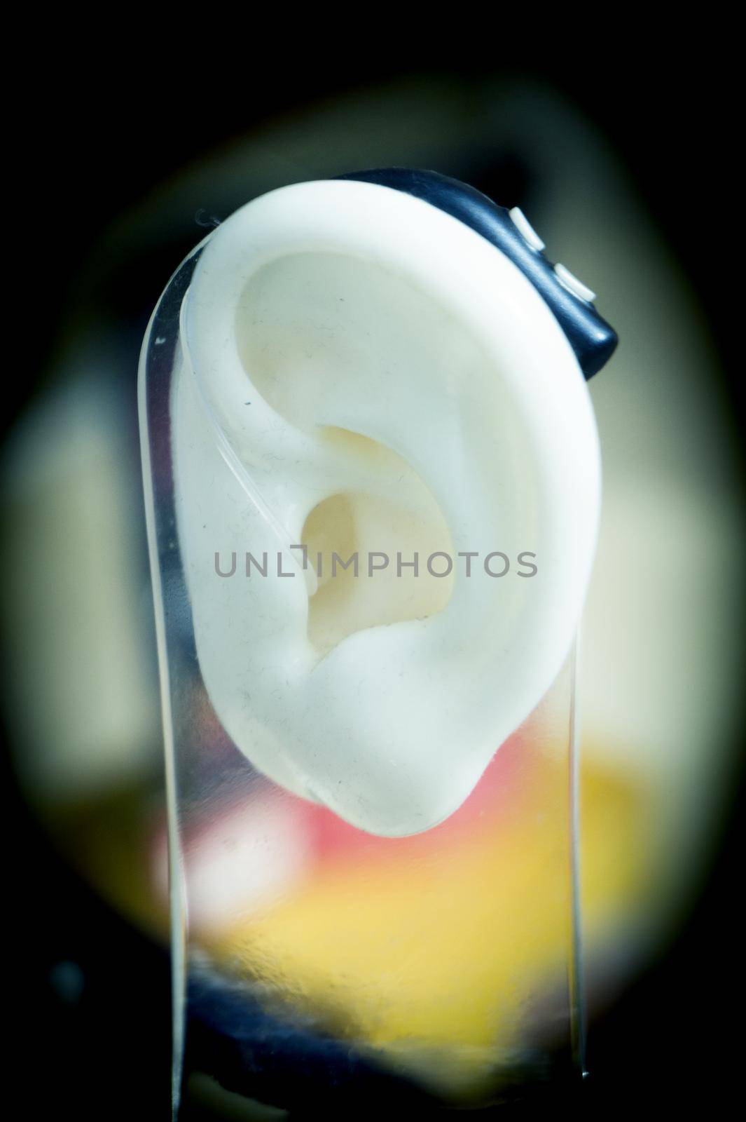 Plastic ear with modern hearing aid. No people