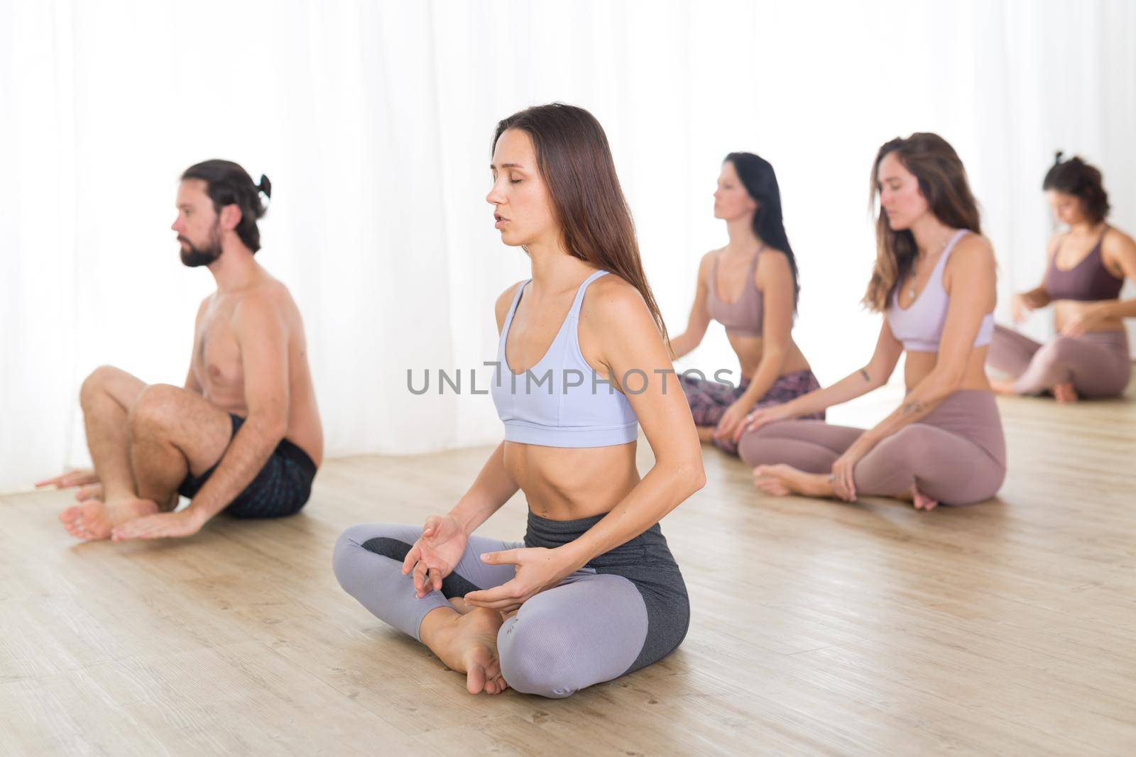 Group of young authentic sporty attractive people in yoga studio, practicing yoga lesson with instructor. Healthy active lifestyle, working out in gym by kasto