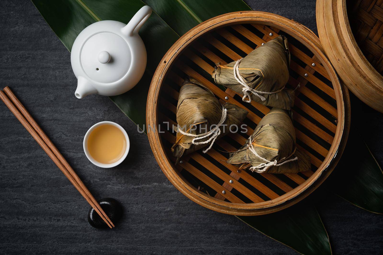 Zongzi Rice dumpling top view for Chinese traditional Dragon Boat Festival (Duanwu Festival) over dark black slate background.