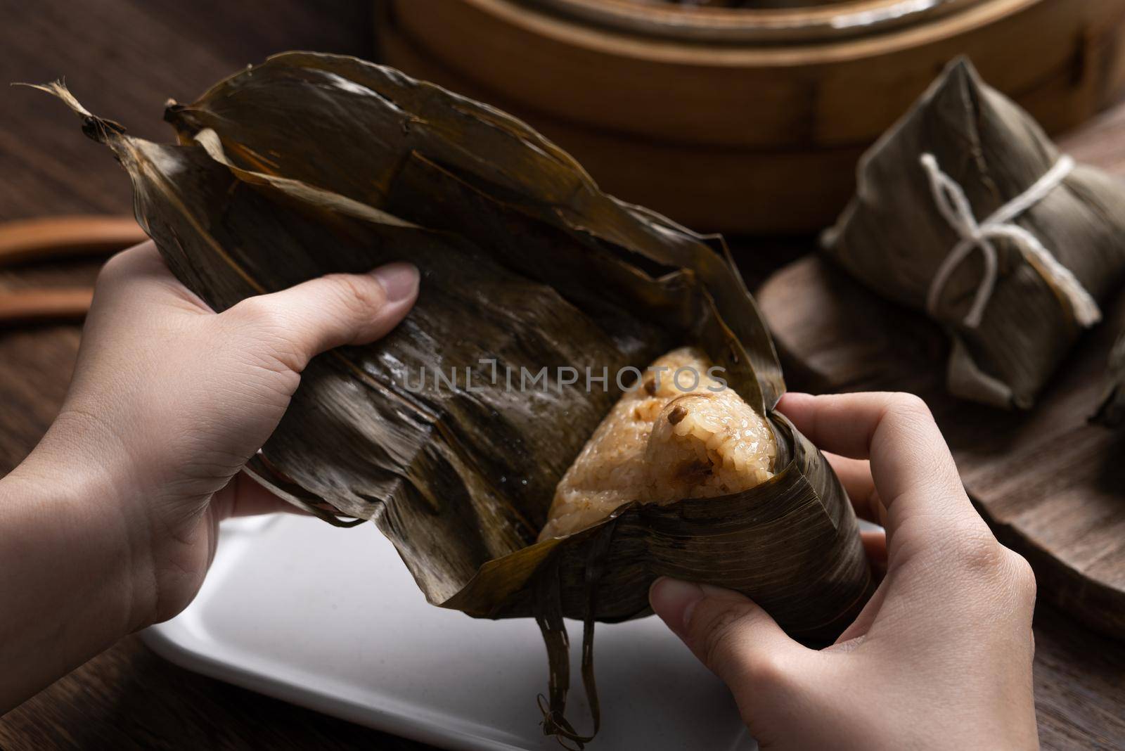 Eating Zongzi rice dumpling for Chinese traditional Dragon Boat Festival (Duanwu Festival) celebration event concept.