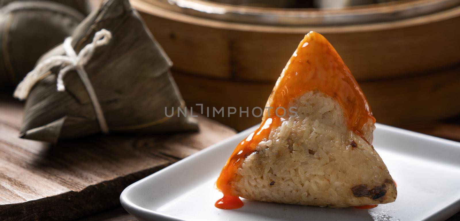 Eating zongzi rice dumpling for Dragon Boat Festival celebration. by ROMIXIMAGE