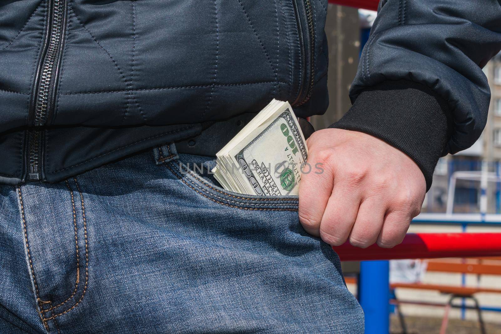 A rich and powerful man pulls out a large wad of money from his jeans pocket