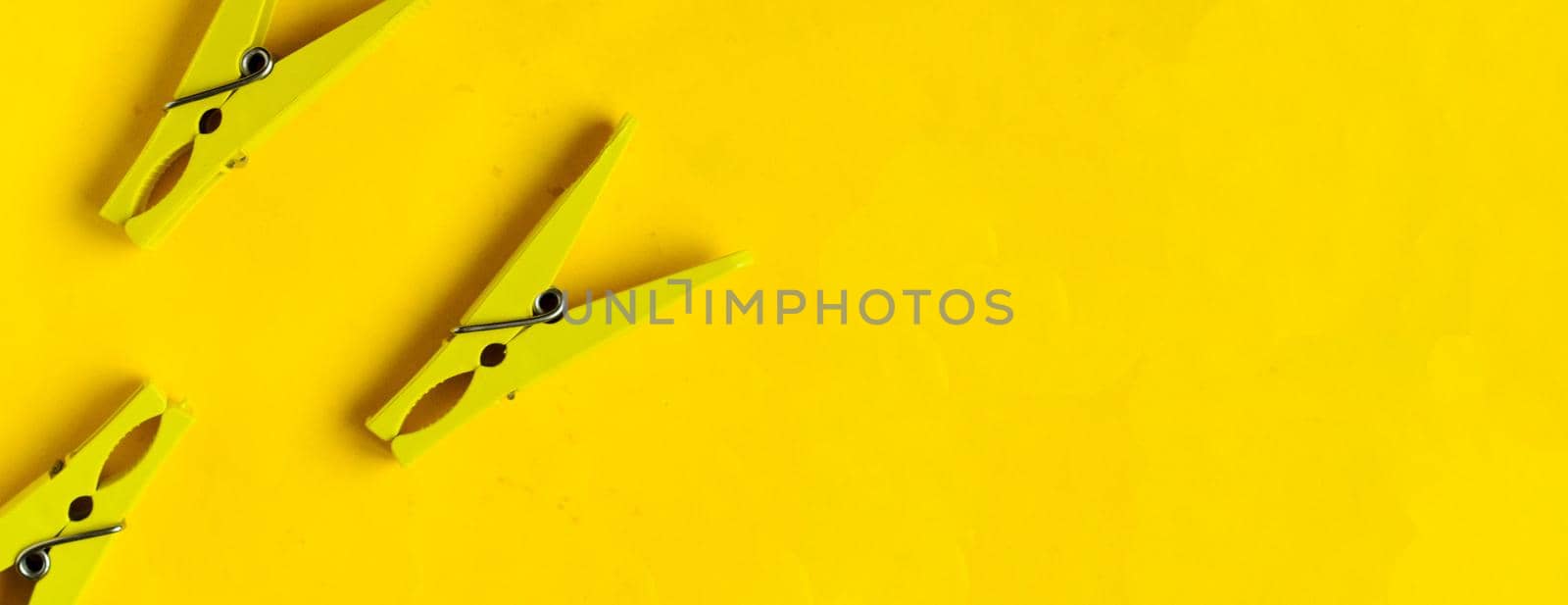 Top view, yellow clothespins on a yellow background, copyspace.