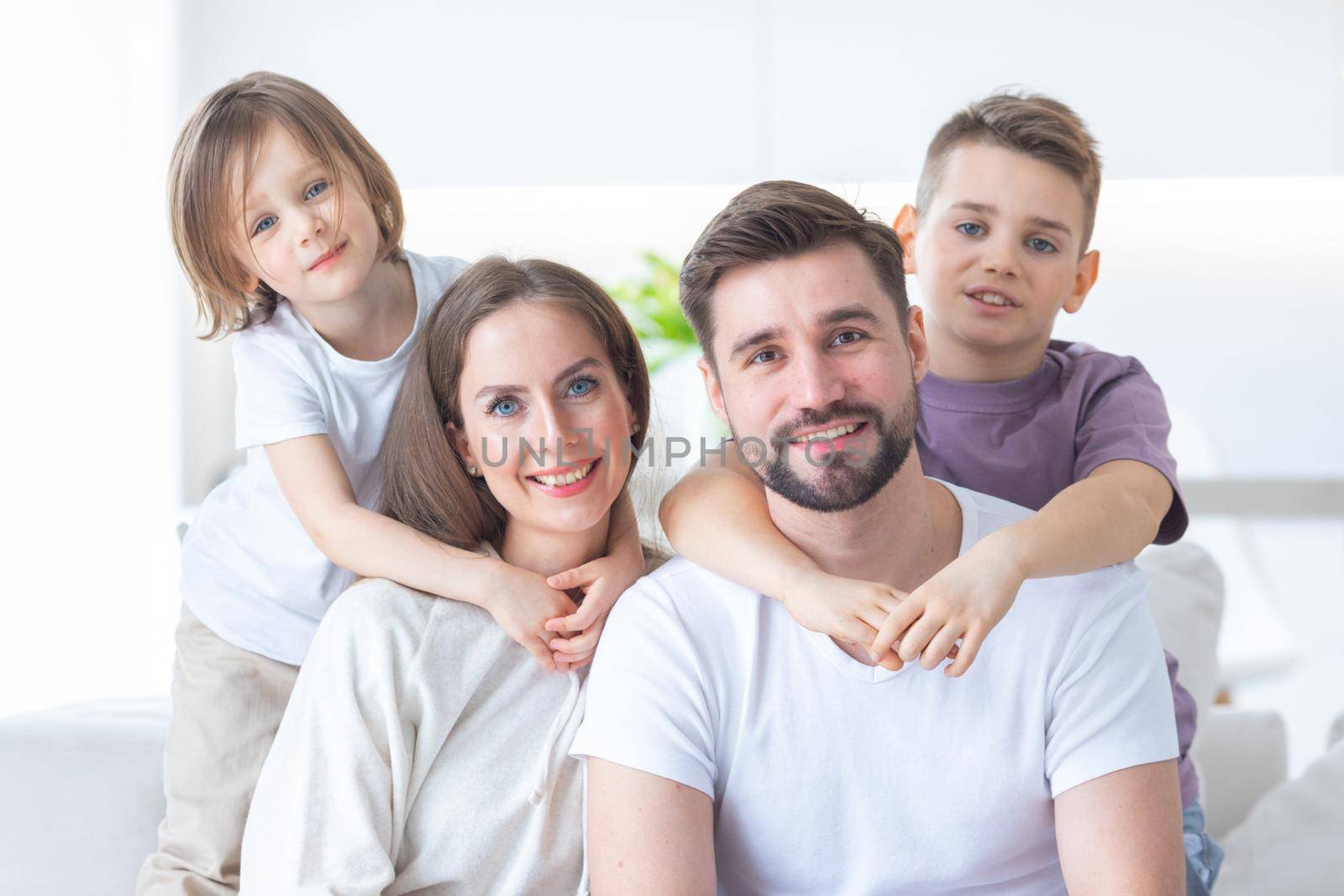 Domestic family portrait, young parents and their two children at home, togetherness, unity, happy childhood