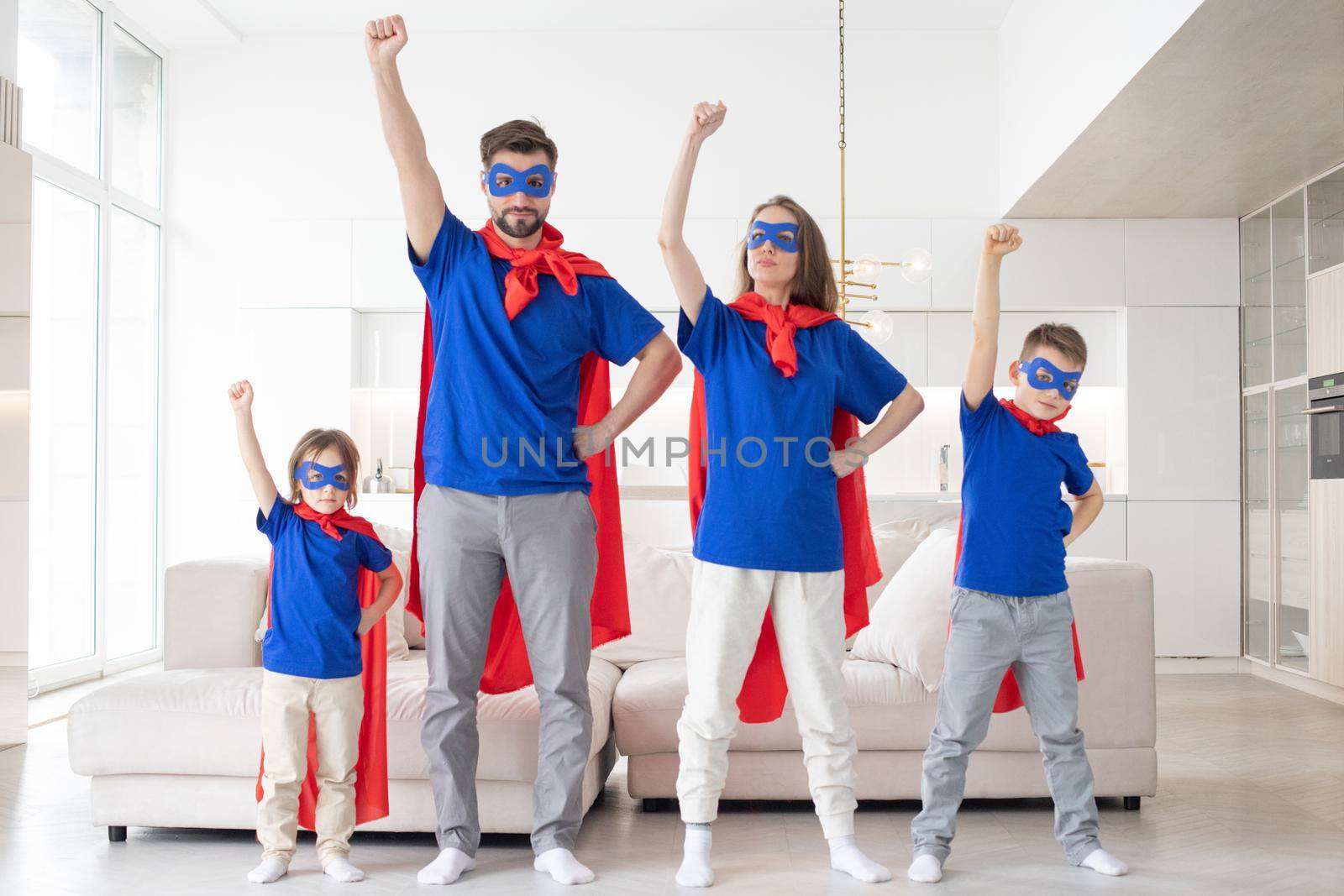 Family of superheroes having fun at home, parents and two children