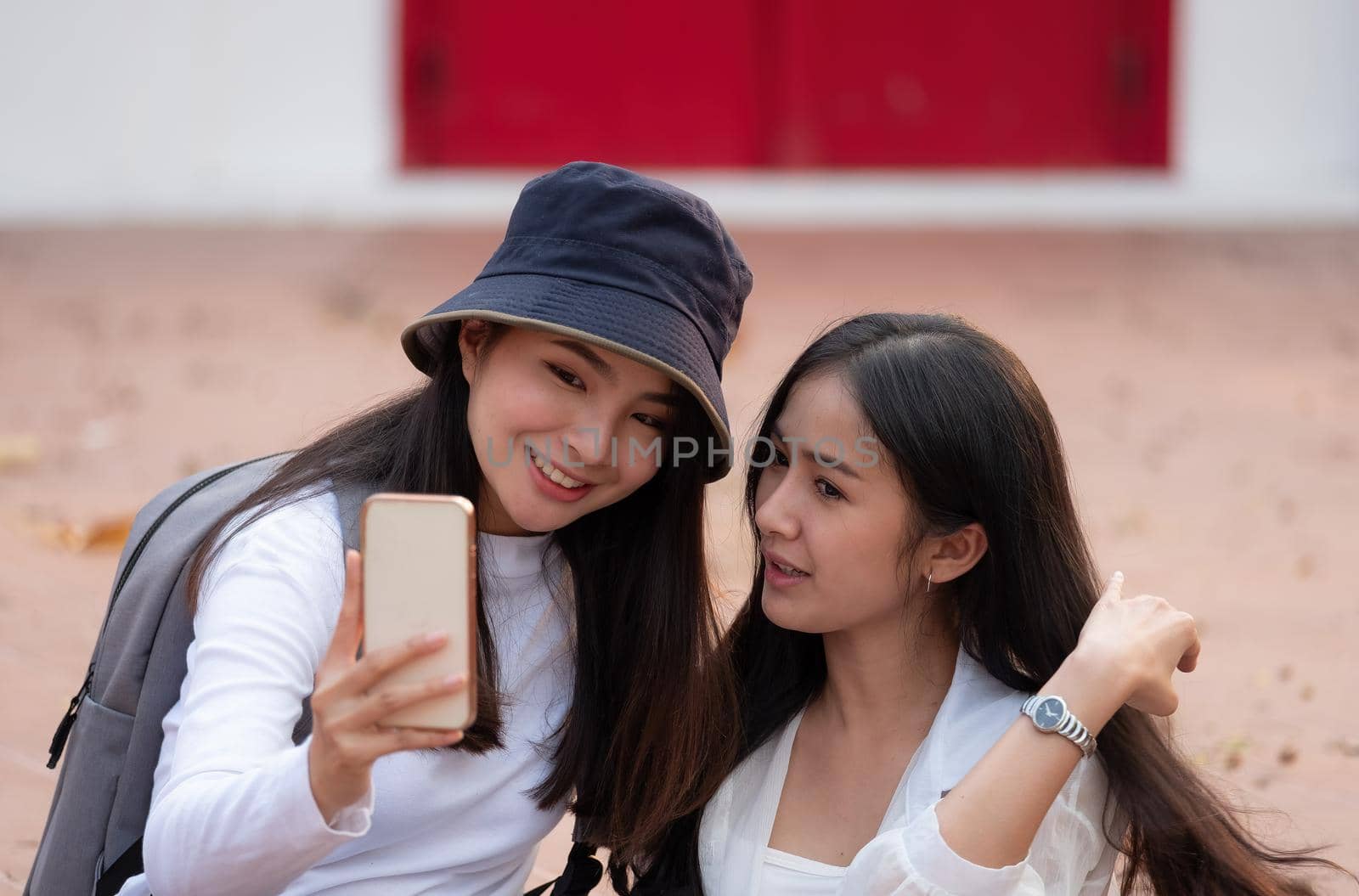Asian women, holding looking on smartphones. making selfie with friends and smiling