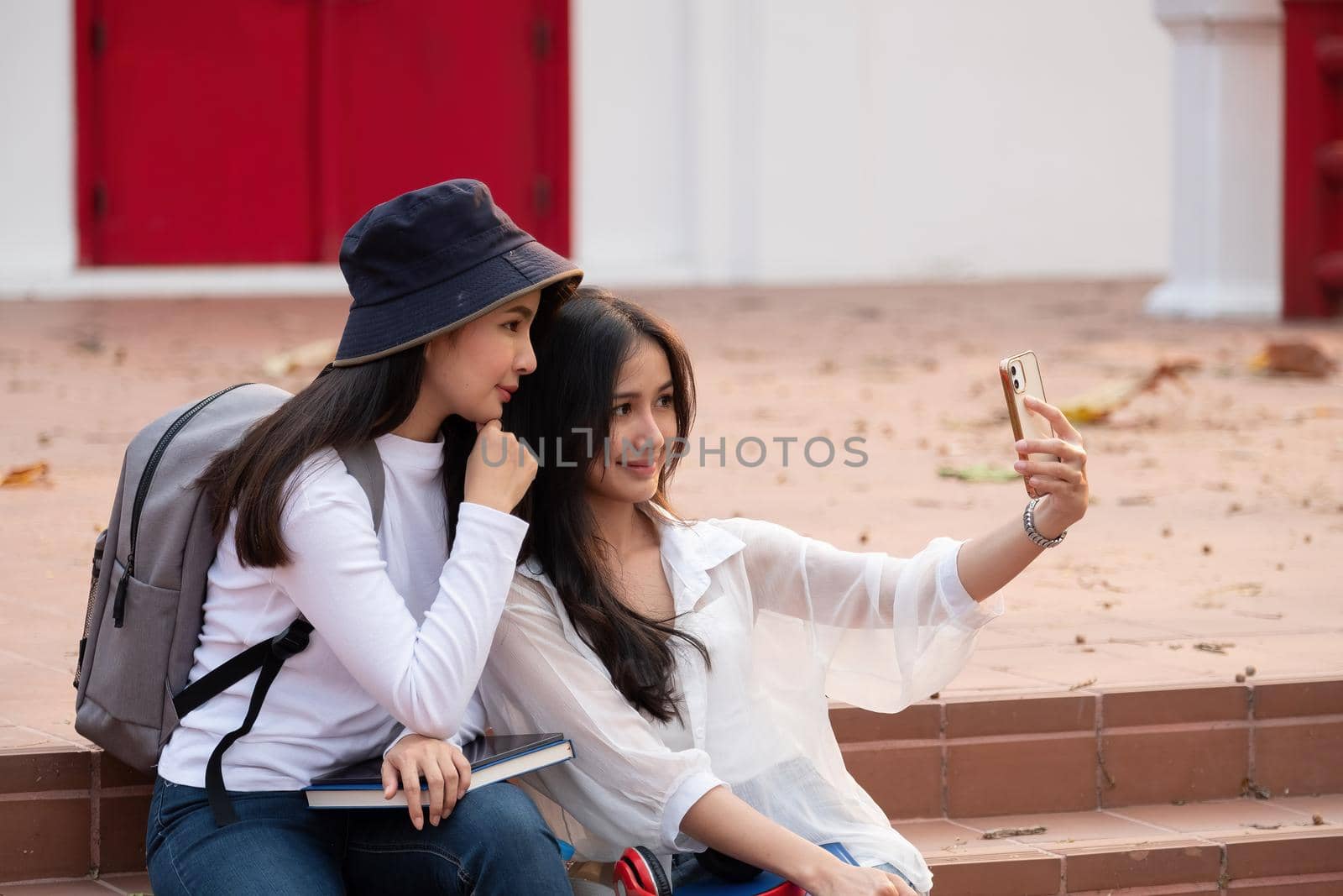 Two students with beaming smiles are posing for selfie shot, Asian attractive lady is taking in university or campus