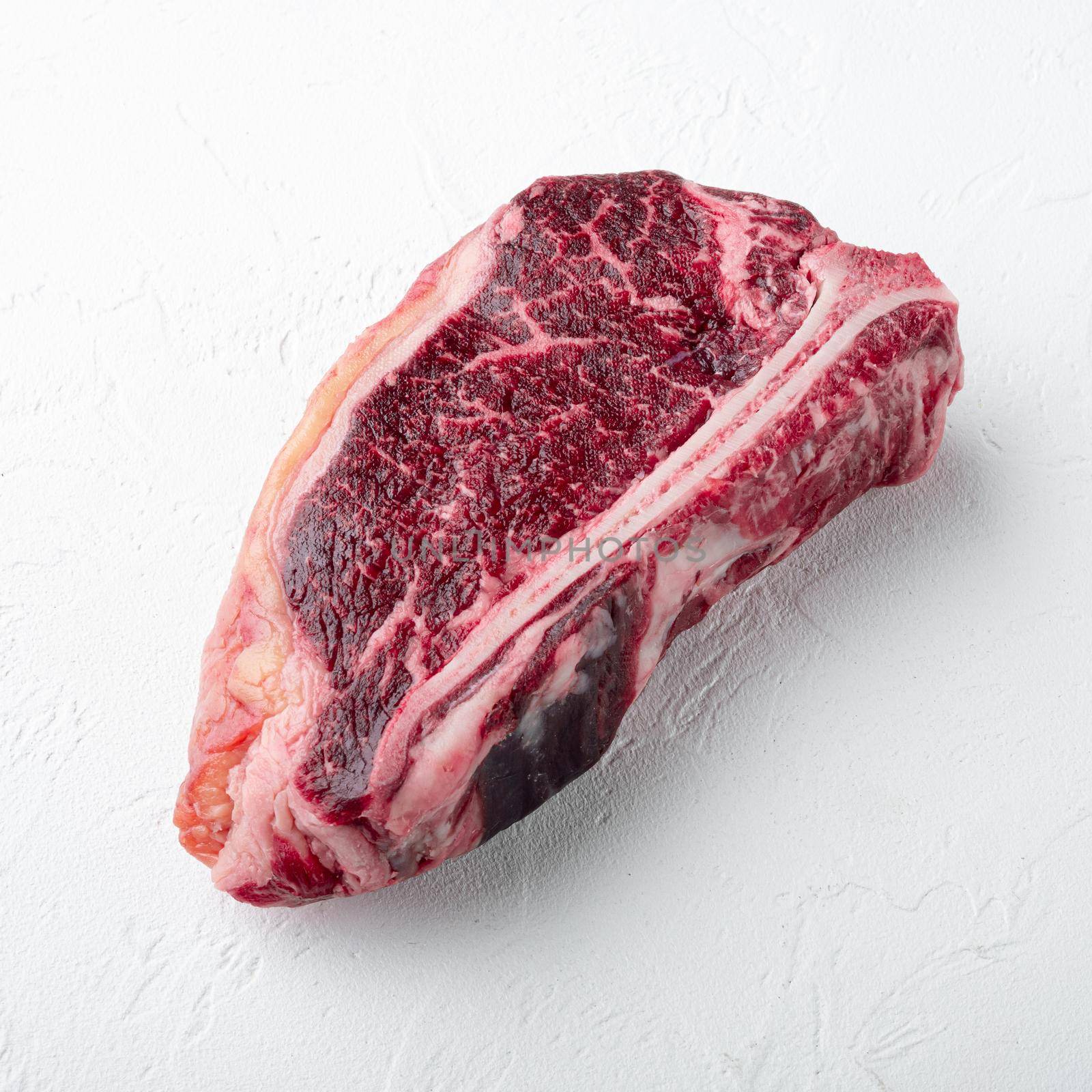 Dry aged club steak, square format, on white stone surface by Ilianesolenyi