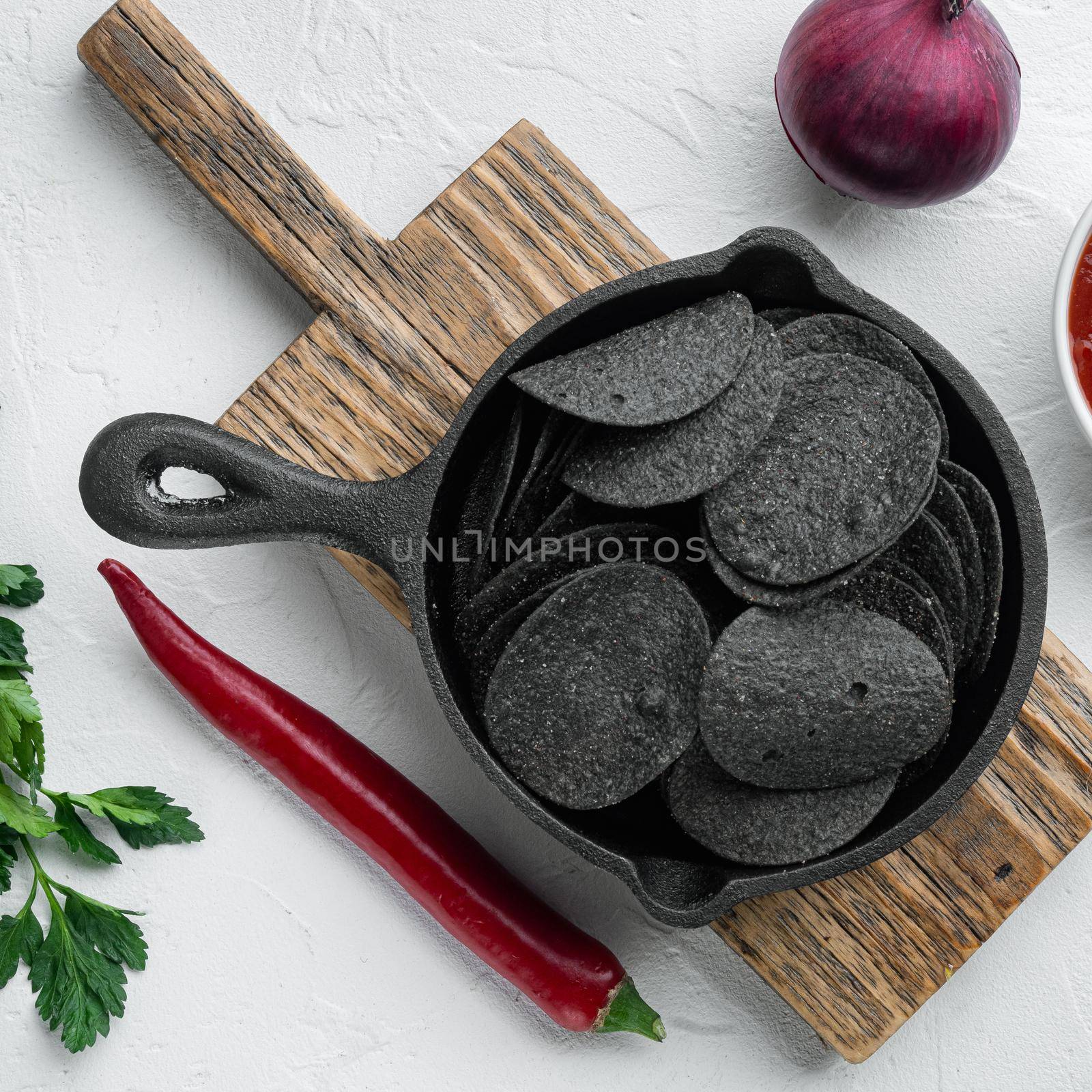 Cheese and chive potato crisp snack set, in cast iron frying pan, on white stone surface, top view flat lay