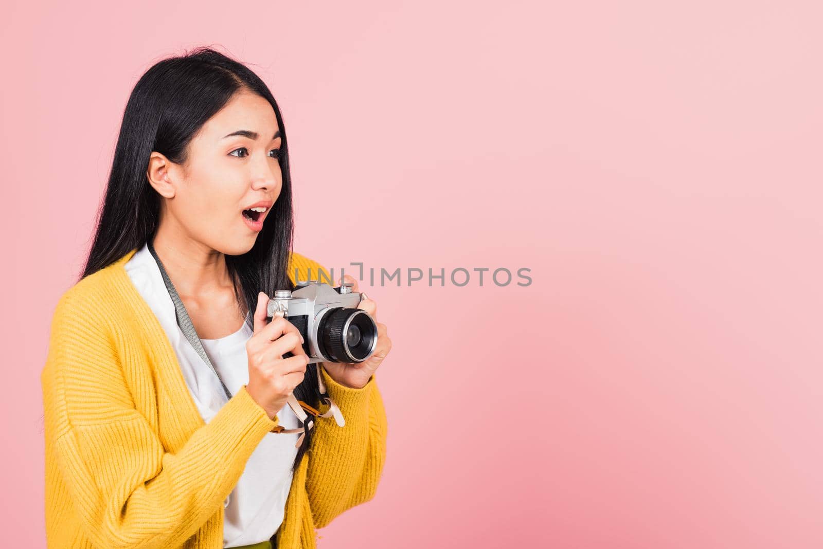 Attractive happy Asian portrait lifestyle beautiful young woman excited smiling photographer holding retro vintage photo camera ready to shoot isolated on pink background, tourism and vacation concept