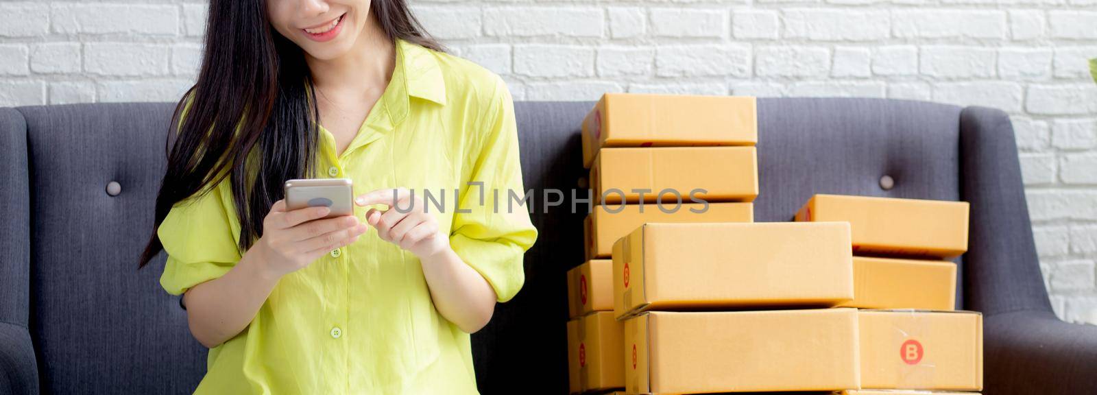 Young asian woman is entrepreneur check order from smartphone with customer while purchase online, logistic and delivery, online shopping, female is seller of business SME, merchant looking phone.