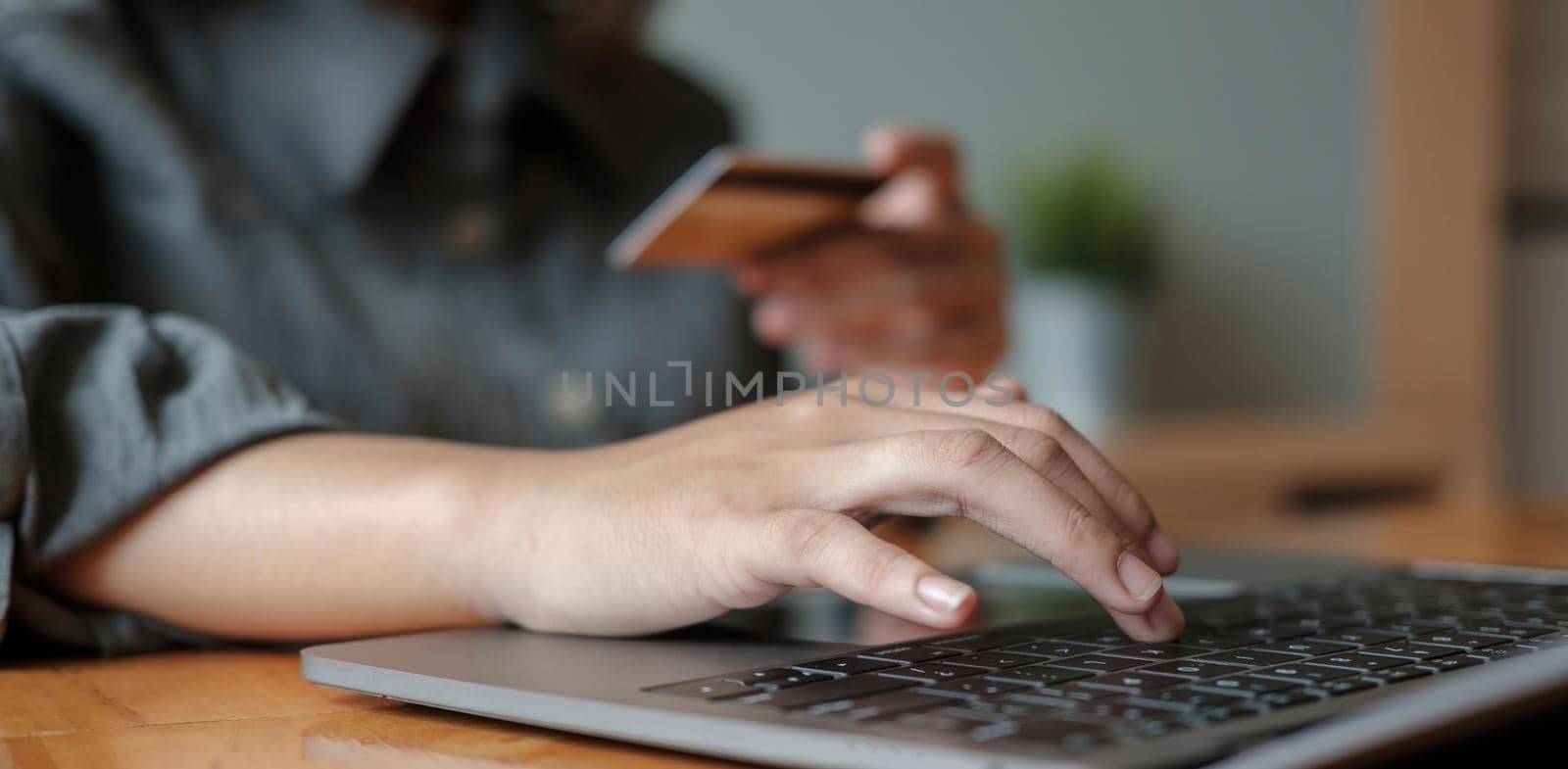 woman hand holding credit card with using laptop for online shopping while making orders at home. business, lifestyle, technology, ecommerce, digital banking and online payment concept. by wichayada