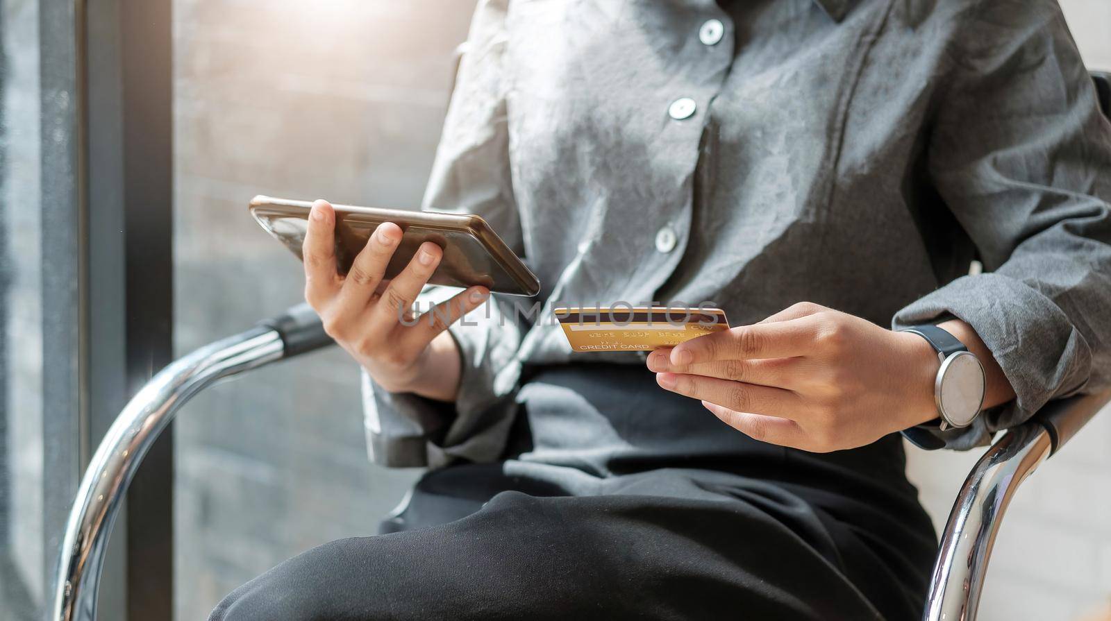 Online payment woman's hands holding a credit card and using smart phone for online shopping by wichayada