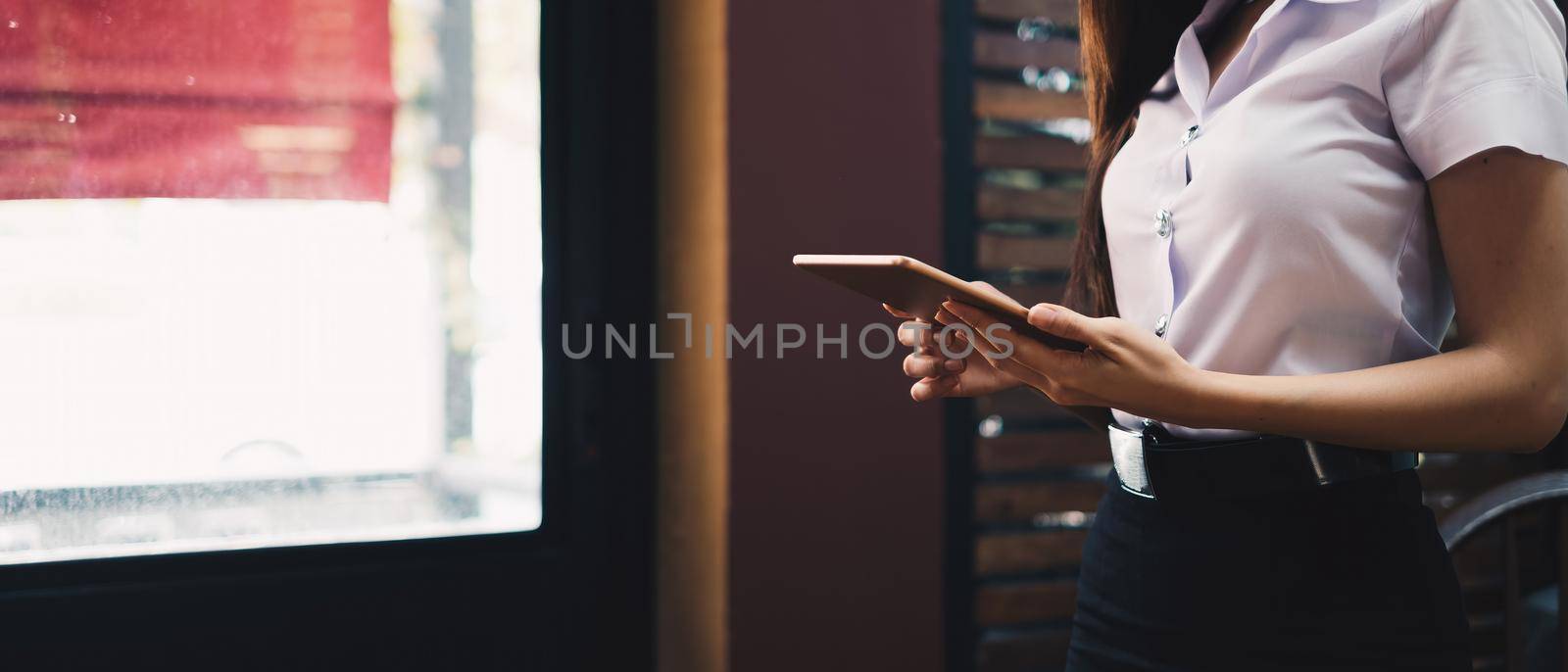 Cropped shot of female holding digital tablet touchscreen in hand, woman working on modern tech gadget in office with copy space.. by nateemee