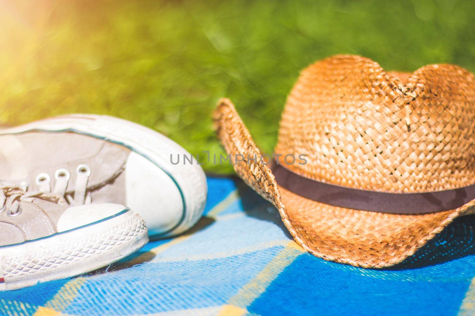 Picnic blanket with sneakers and straw hat