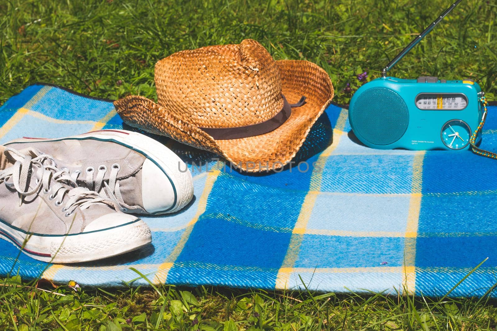 Picnic blanket with sneakers, straw hat, and radio