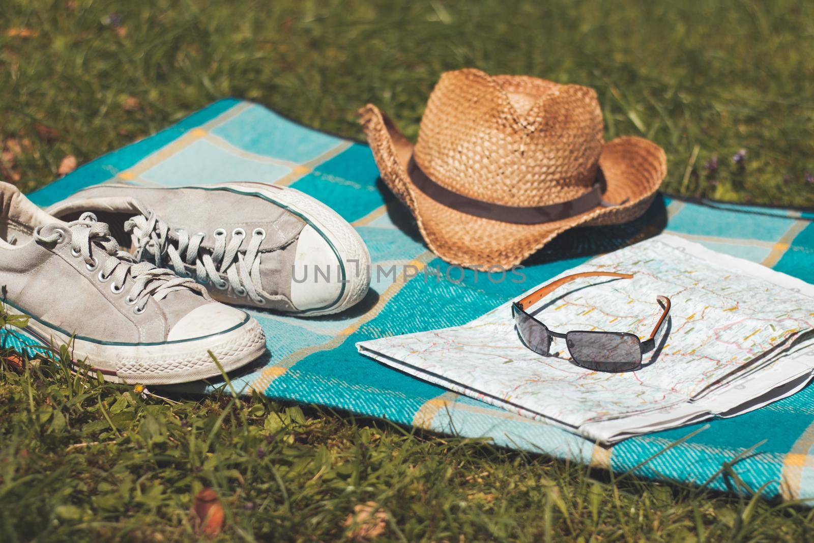 Chilling in the summer concept: picnic blanket with sneakers, straw hat, map and radio by Daxenbichler