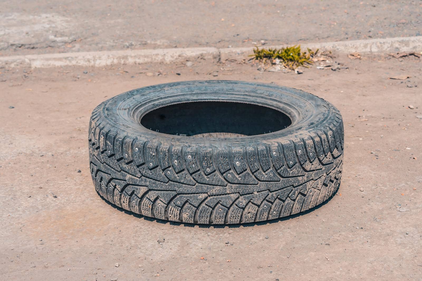 Thrown out on a deserted road, an old, worn-out winter tire from a car wheel