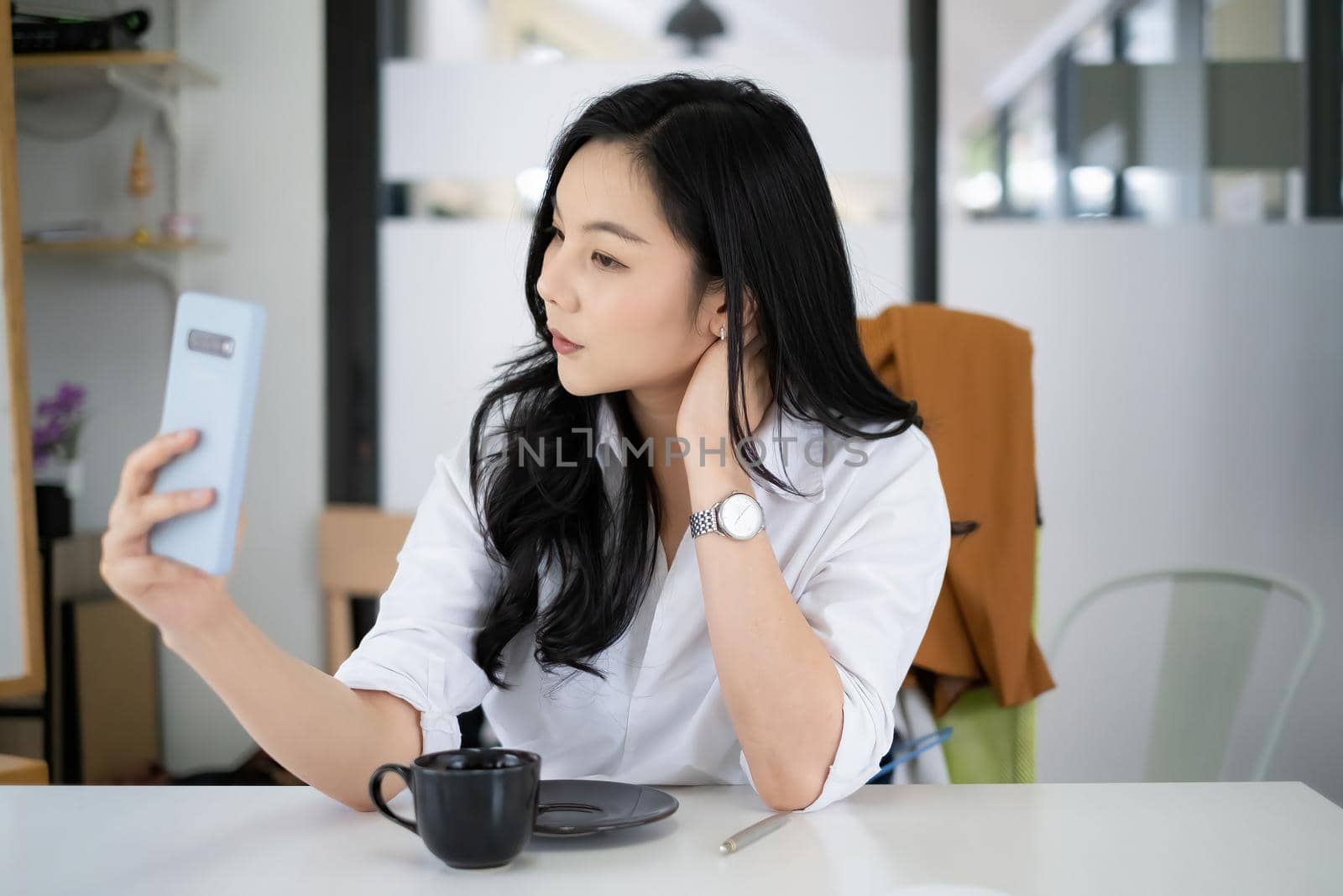 Portrait of Asian female business financial checking her port stock market in mobile application at morning with coffee