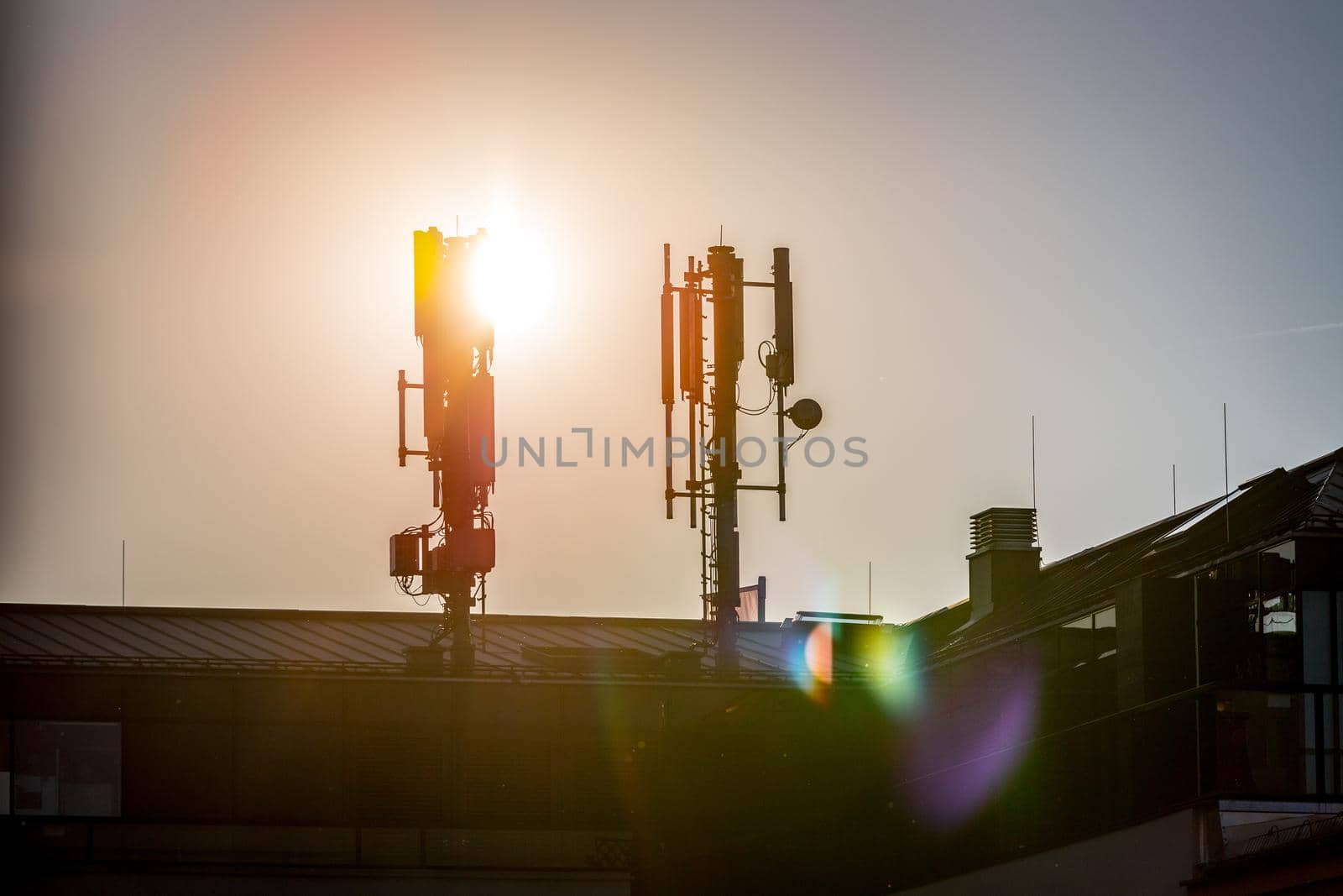 Silhouette of communication or cell tower on the rooftop of a building, evening sunshine