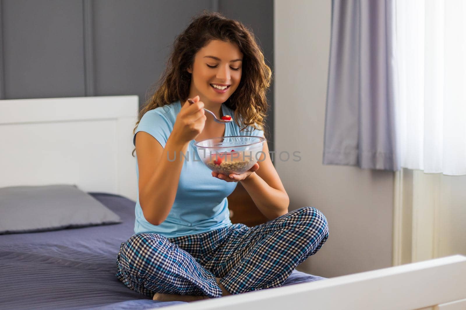 Beautiful woman enjoys eating cereals for breakfast.