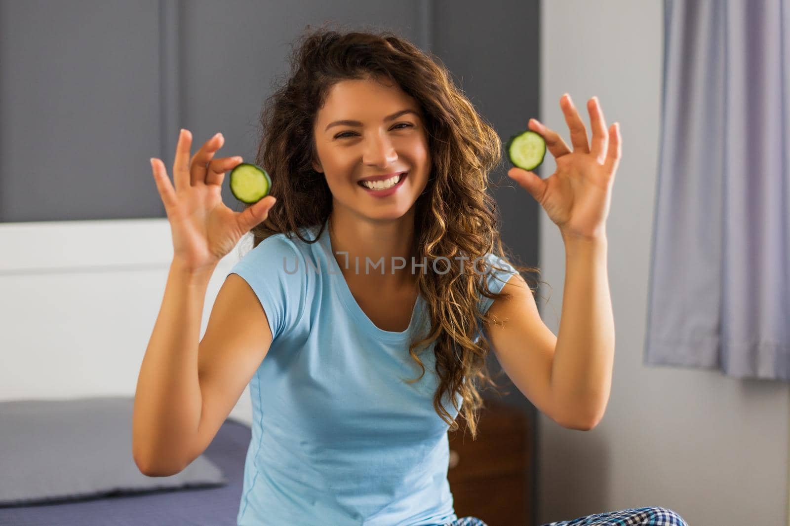 Woman is doing home beauty treatment with cucumber by Bazdar