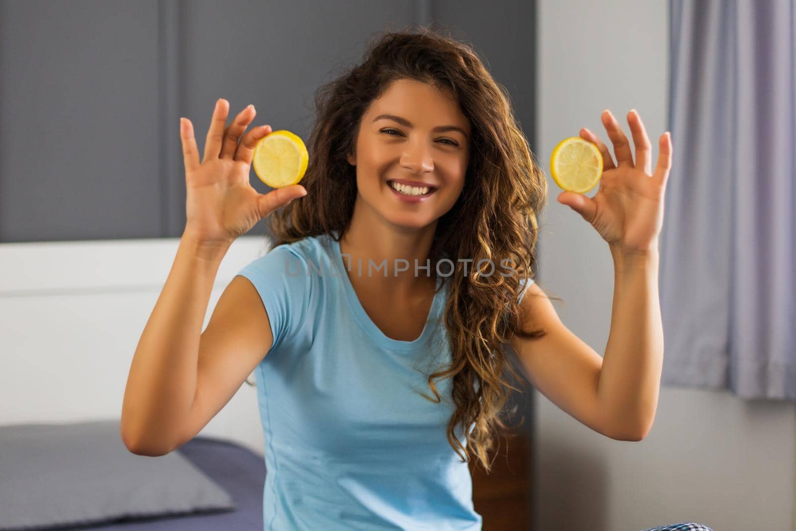 Beautiful woman is doing home beauty treatment with lemon.