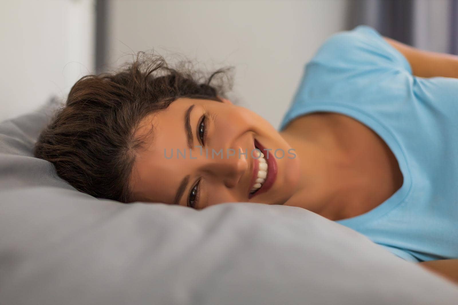 Close up portrait of beautiful woman waking up in her bed.
