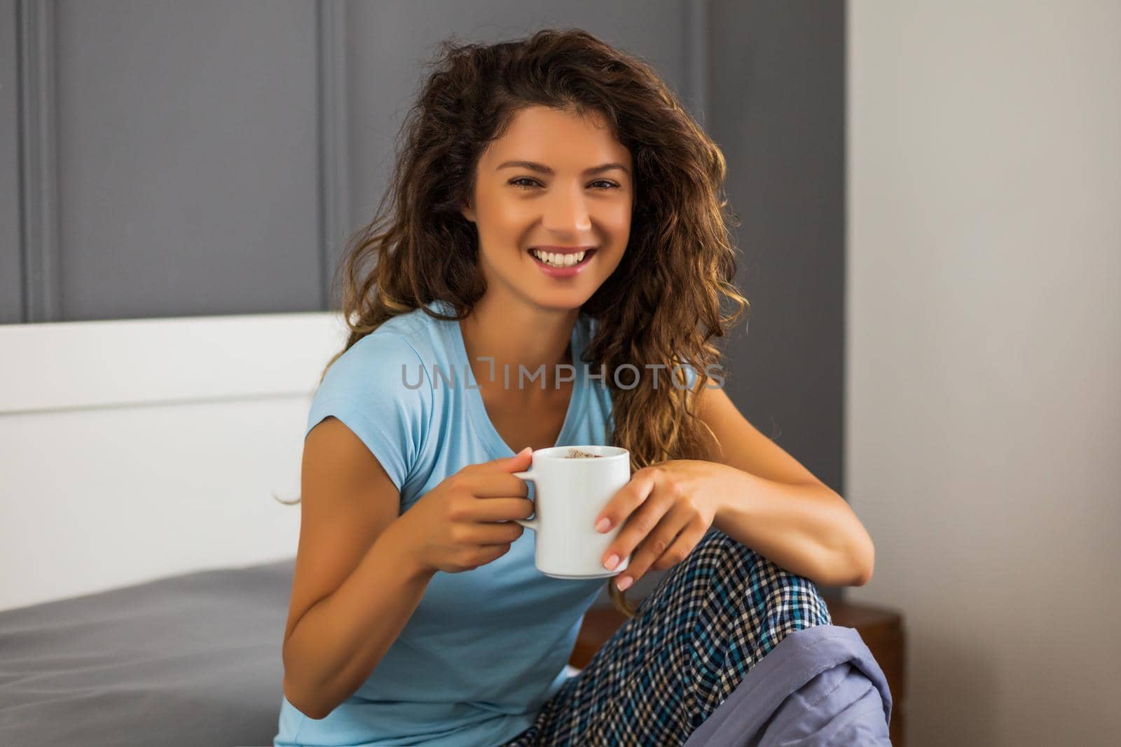 Beautiful woman enjoys drinking coffee in her bed.