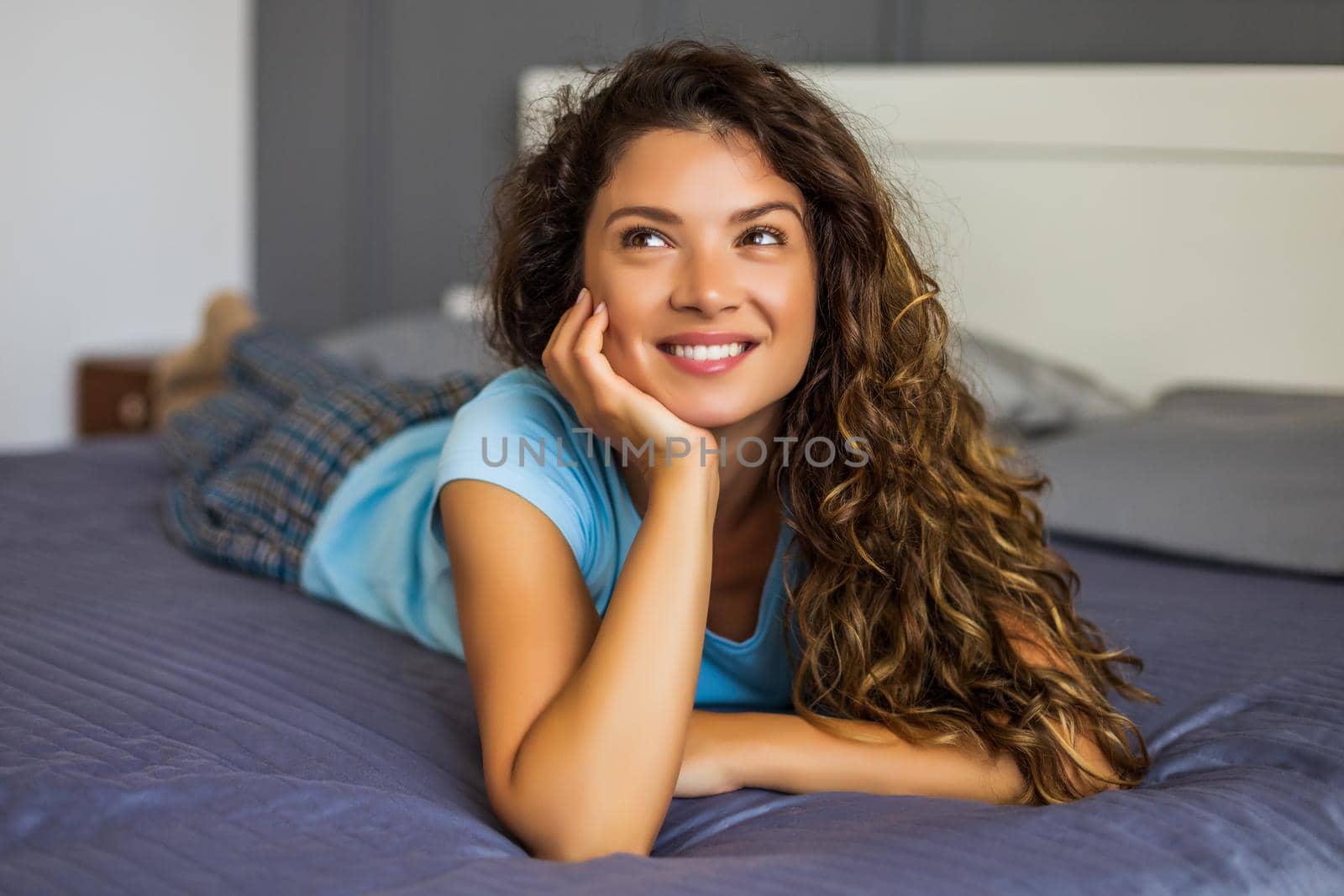 Portrait of happy woman lying on bed.