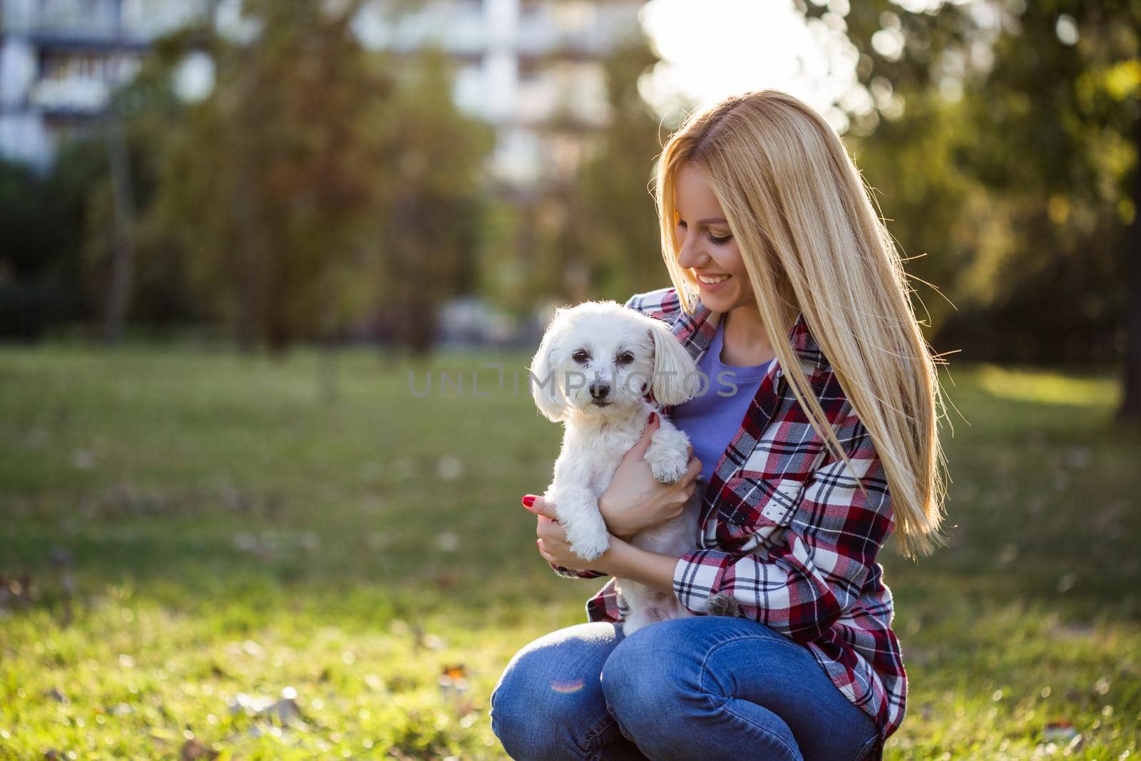 Beautiful woman spending time with her Maltese dog outdoor.