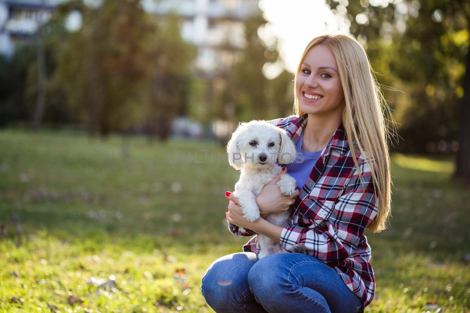 Beautiful woman spending time with her Maltese dog outdoor.