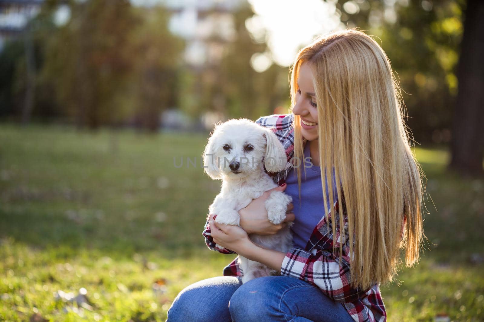 Beautiful woman spending time with her Maltese dog outdoor.