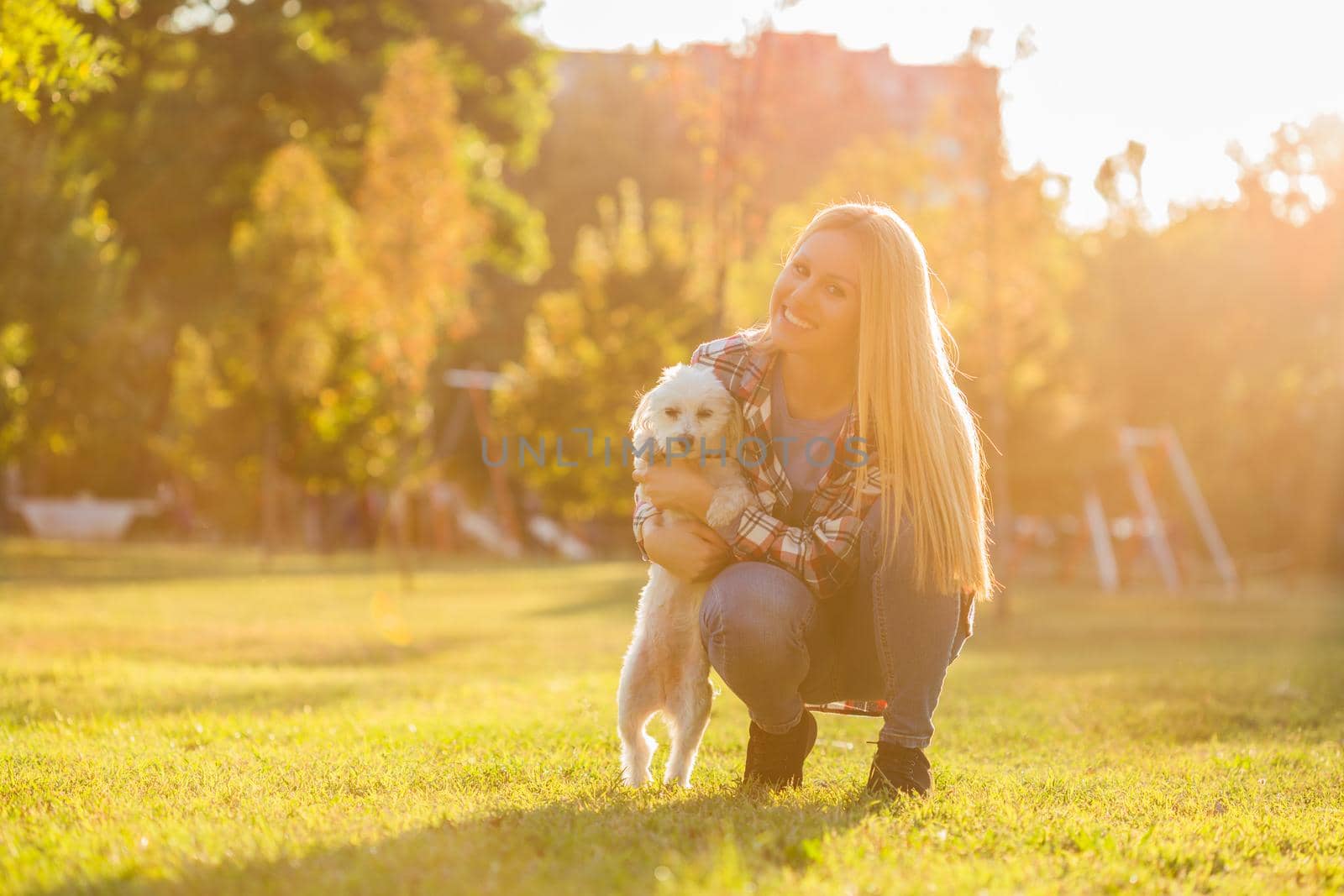 Beautiful woman spending time with her Maltese dog outdoor.