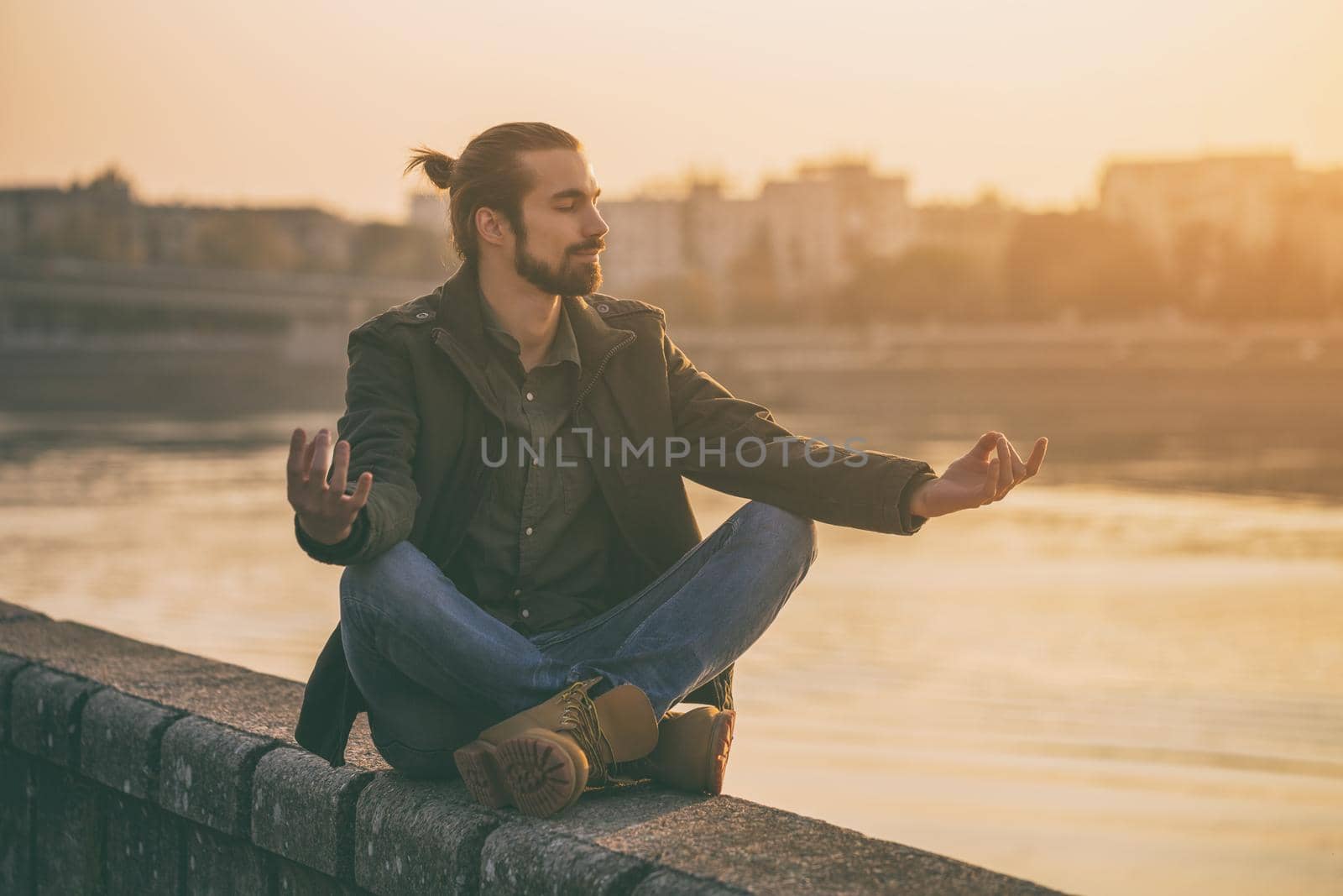 Handsome modern businessman enjoys meditating by the river.
