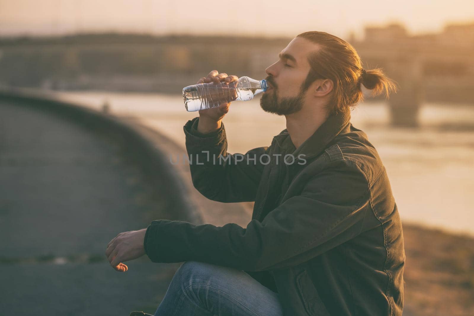 Handsome modern businessman enjoys drinking water and resting by the river.