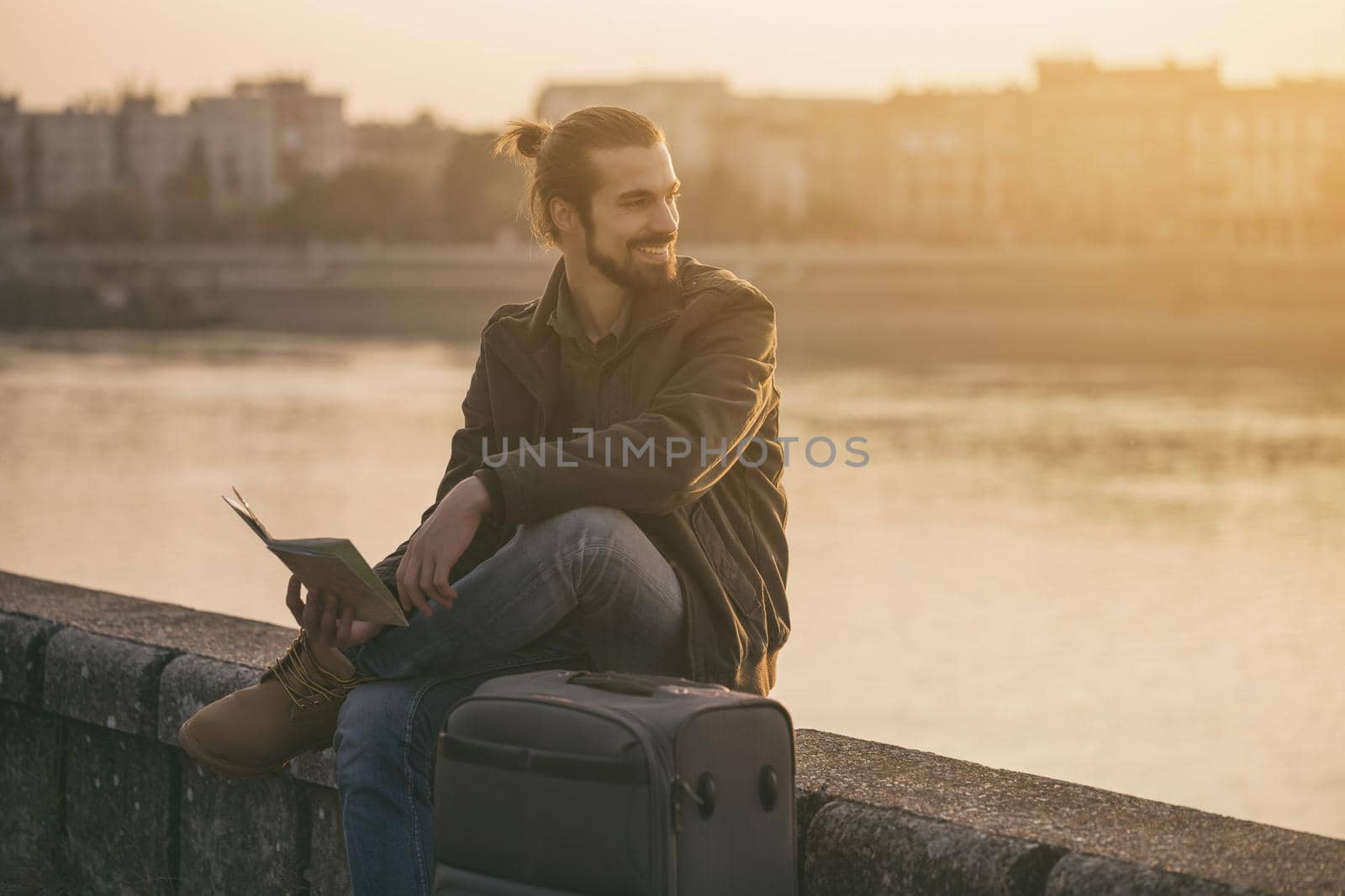 Businessman holding map of the city and sitting by the river by Bazdar