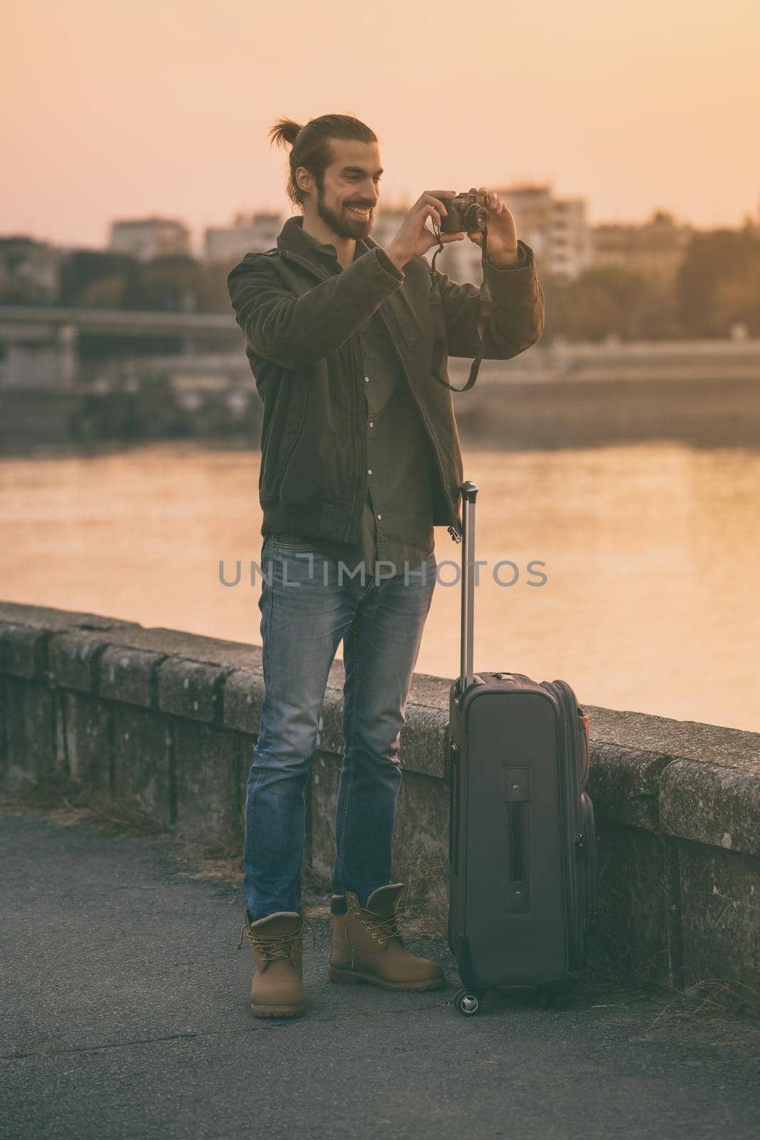 Businessman with suitcase  photographing city by Bazdar