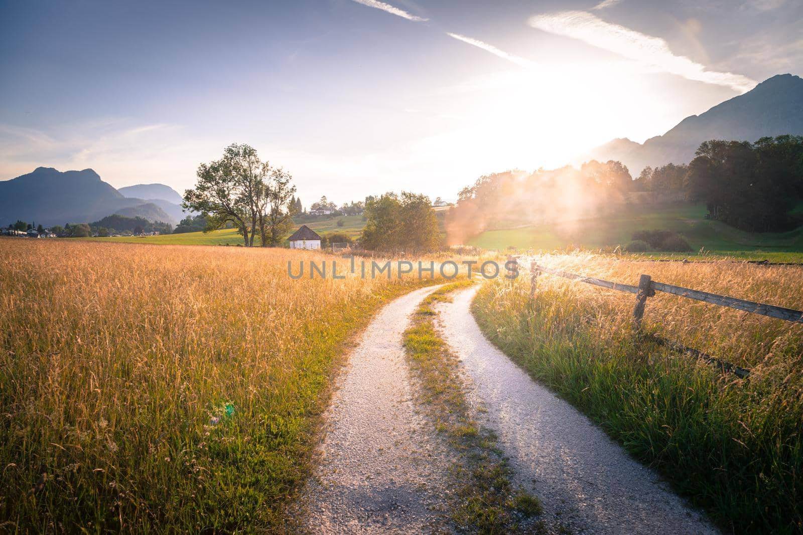 Scenic sunset view over country road, meadow, hills and mountains.