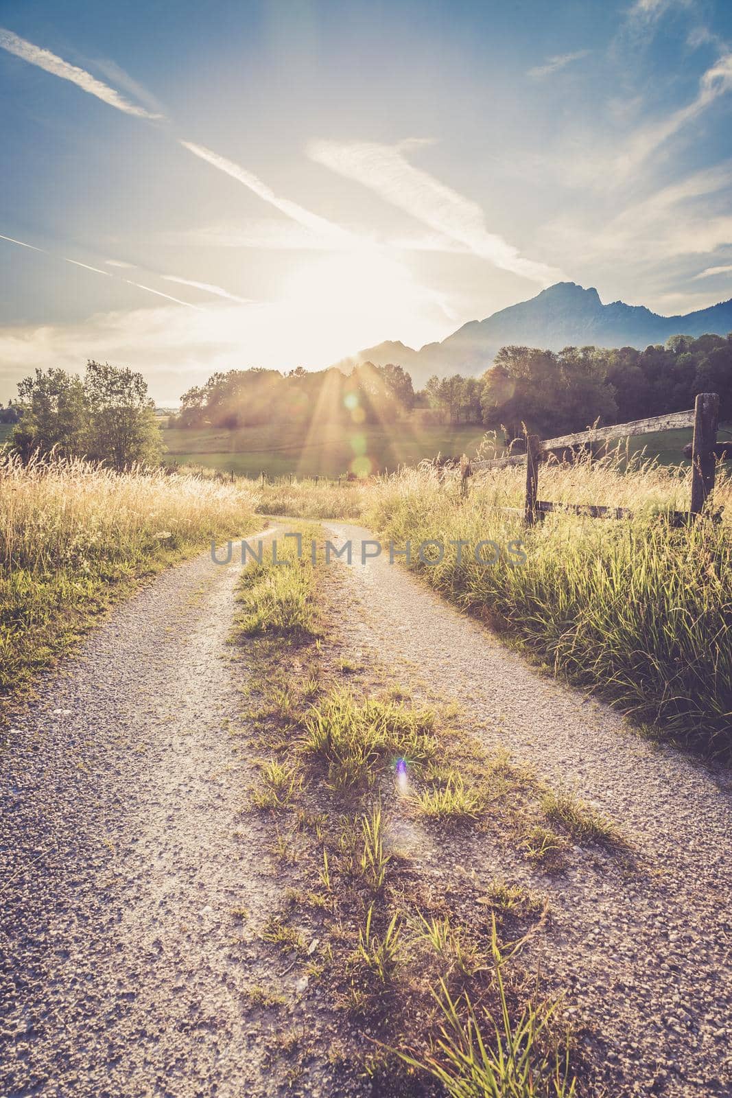 Scenic sunset view over country road, meadow, hills and mountains.