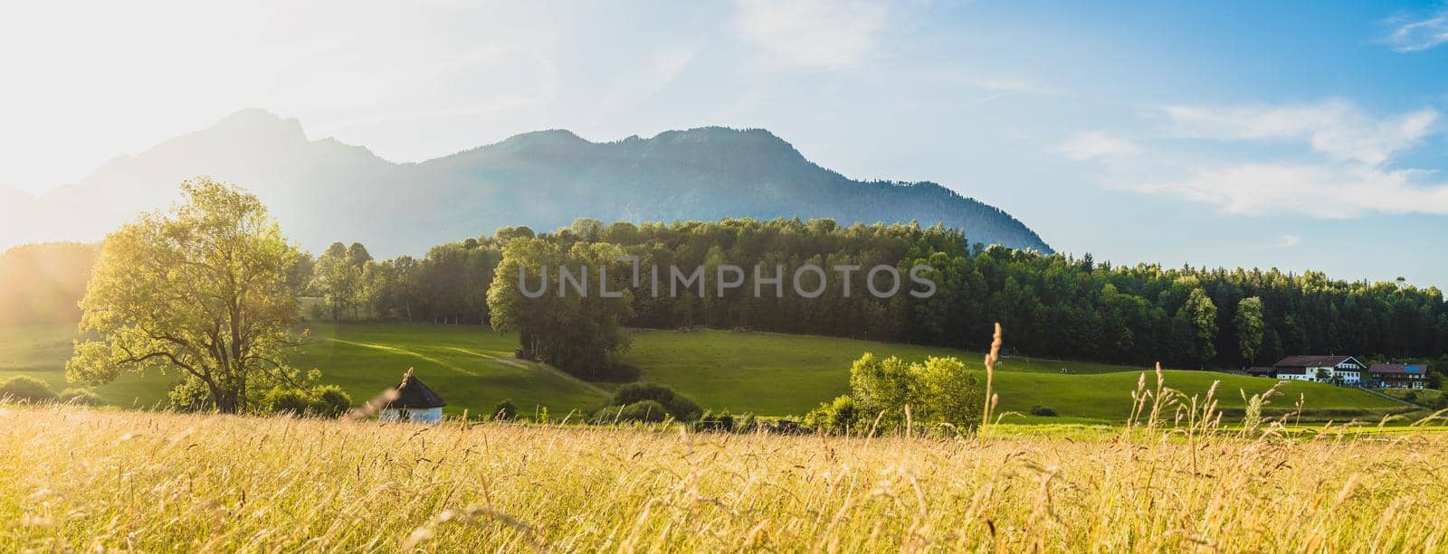 Scenic sunset view over meadow, hills and mountains.