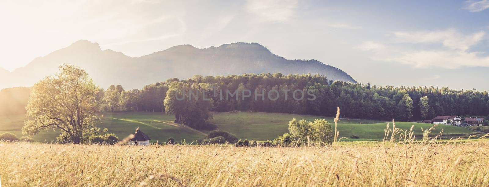 Scenic sunset view over meadow, hills and mountains.